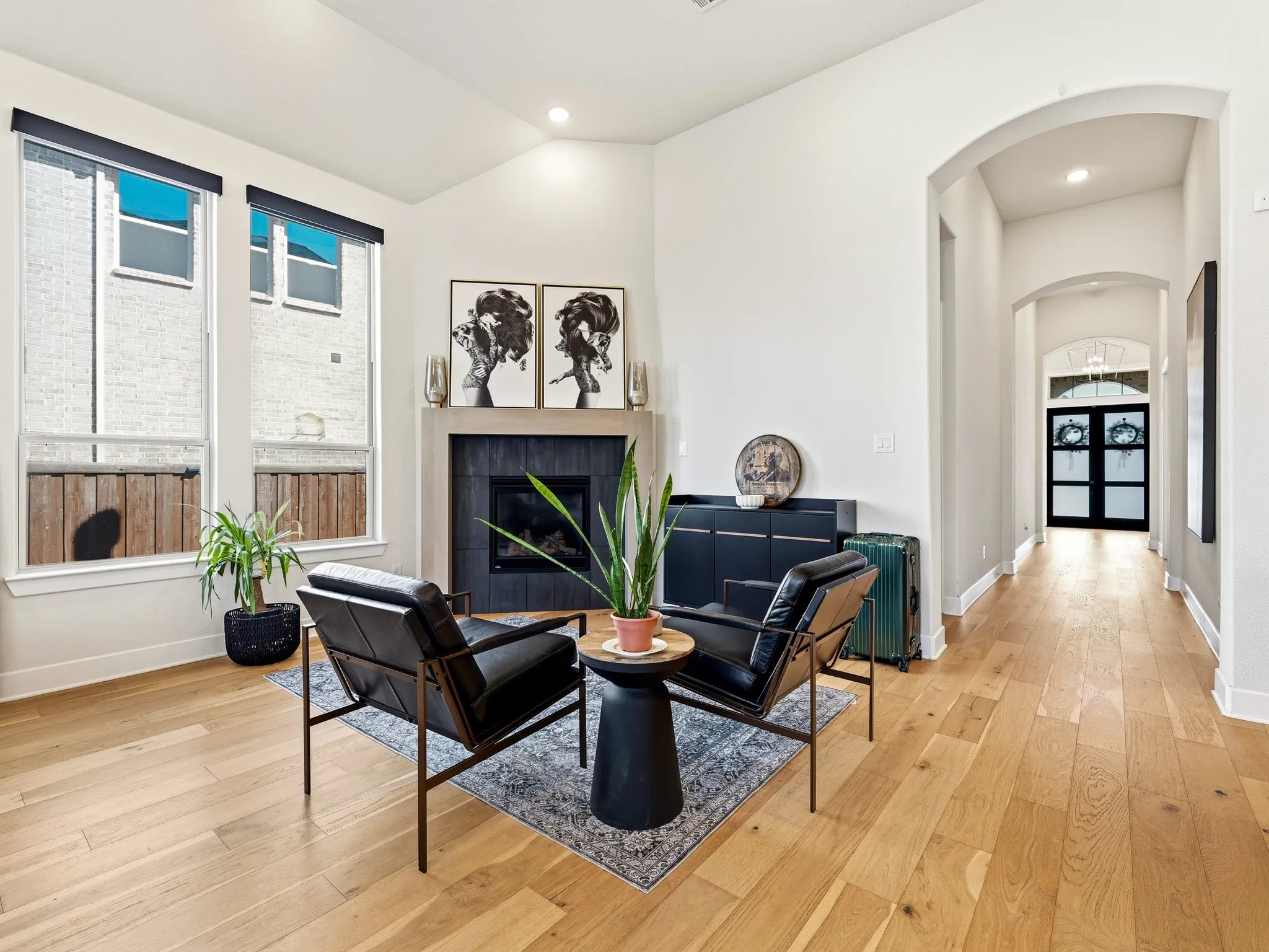 Vaulted ceilings, wood-finish flooring, fireplace with a stone-surround mantel, and arched entryways