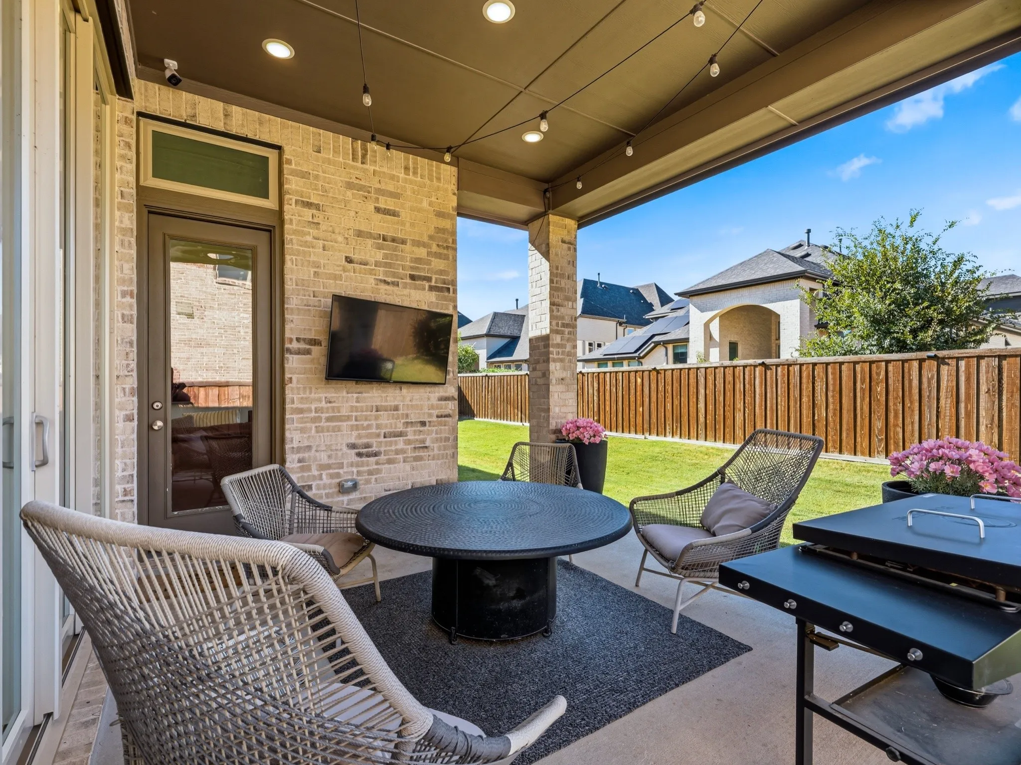 Covered patio featuring a brick exterior wall, recessed ceiling lighting, wall-mounted television, and concrete flooring