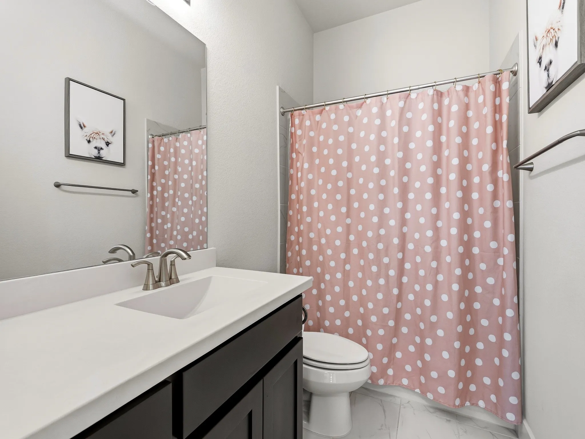 Dark-finish vanity featuring an integrated basin, brushed nickel faucet, large wall-mounted mirror, and tile flooring