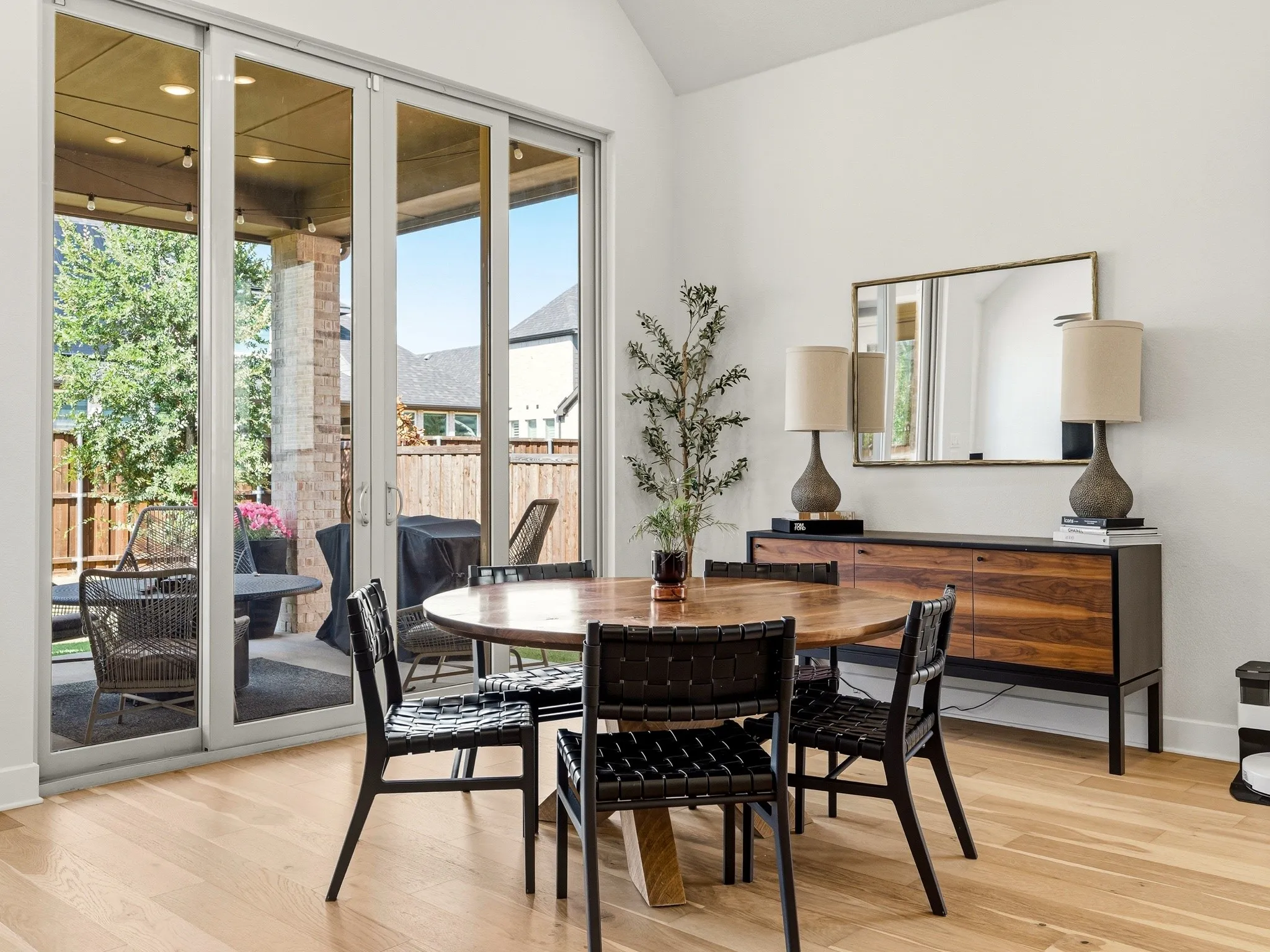 Vaulted ceiling, wood-finish flooring, and multi-panel sliding glass doors opening to a covered patio