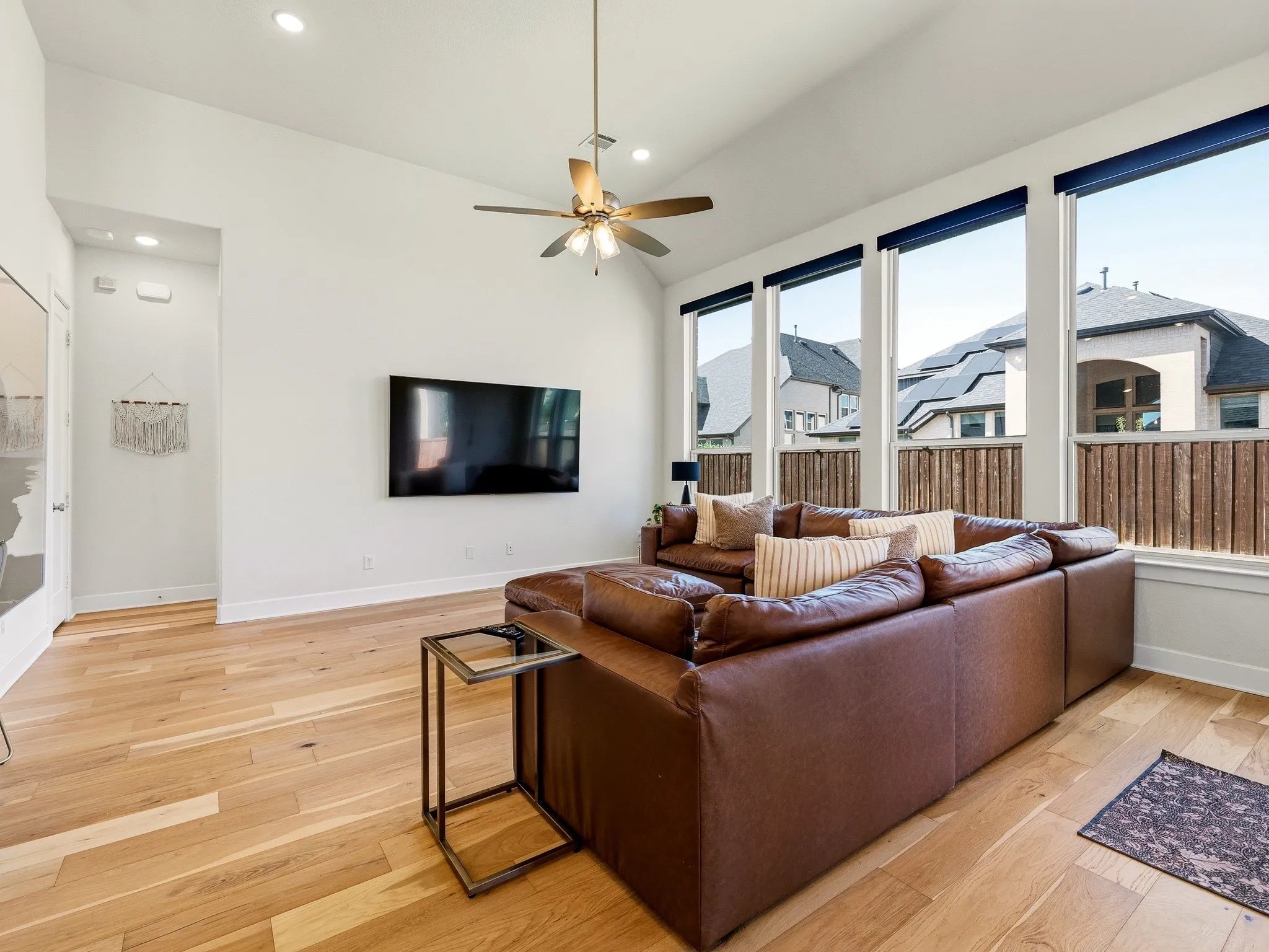 Vaulted ceilings, expansive windows, wood-finish flooring, and integrated ceiling fan