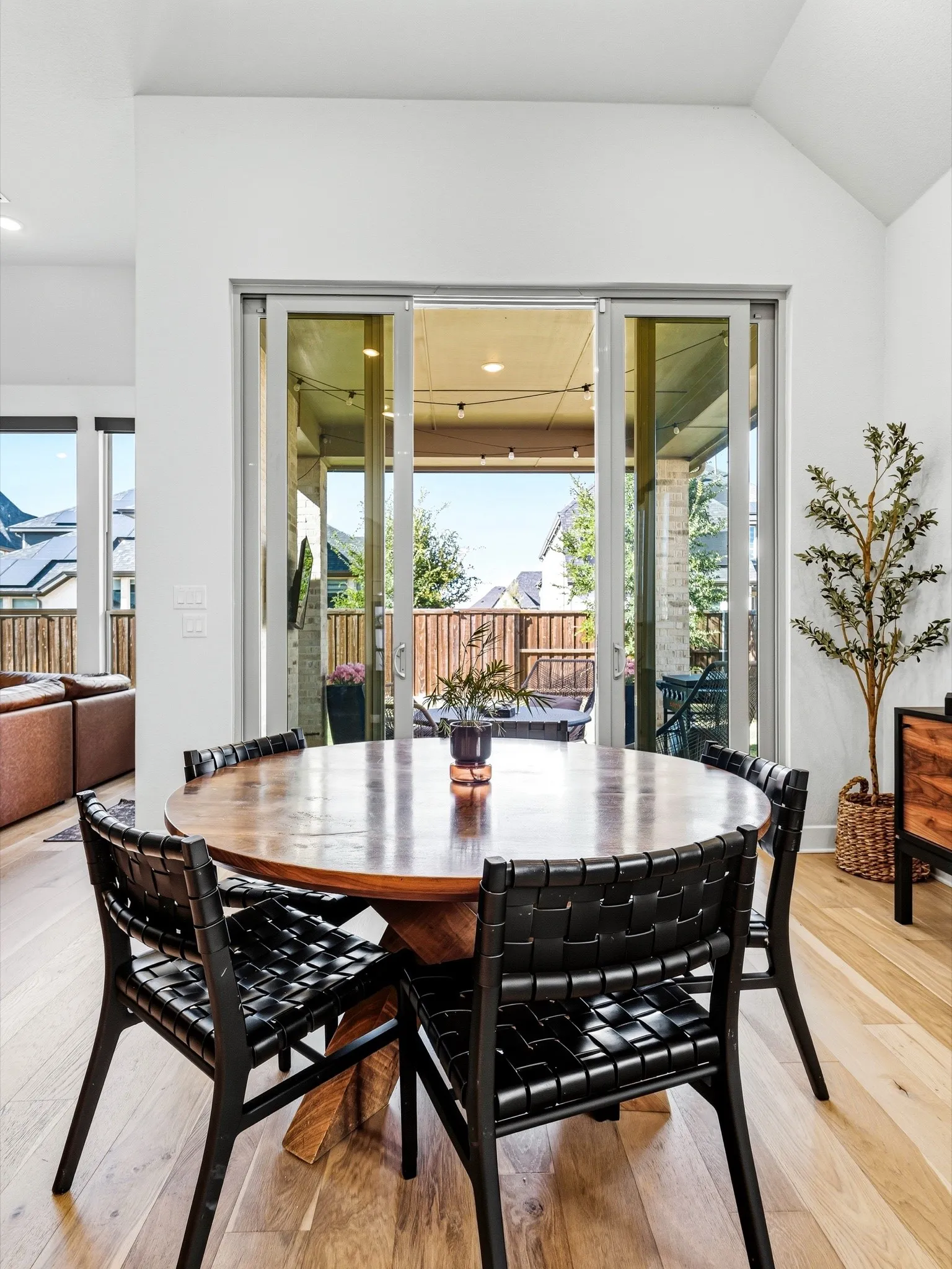 Vaulted ceilings, wood-finish flooring, and multi-panel sliding glass doors opening to a covered patio