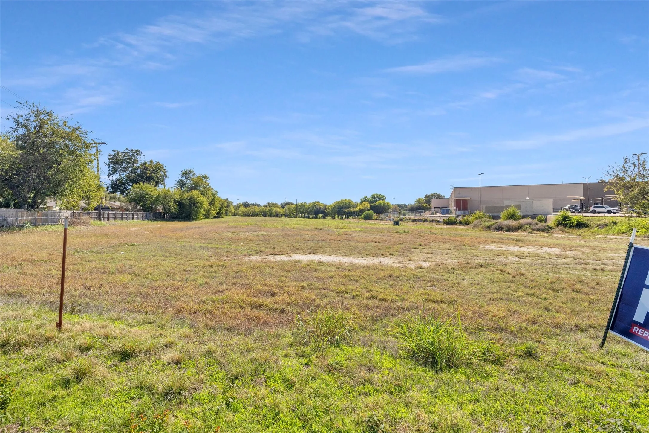 Expansive level parcel featuring open terrain, mature perimeter trees, and a wooden fence boundary