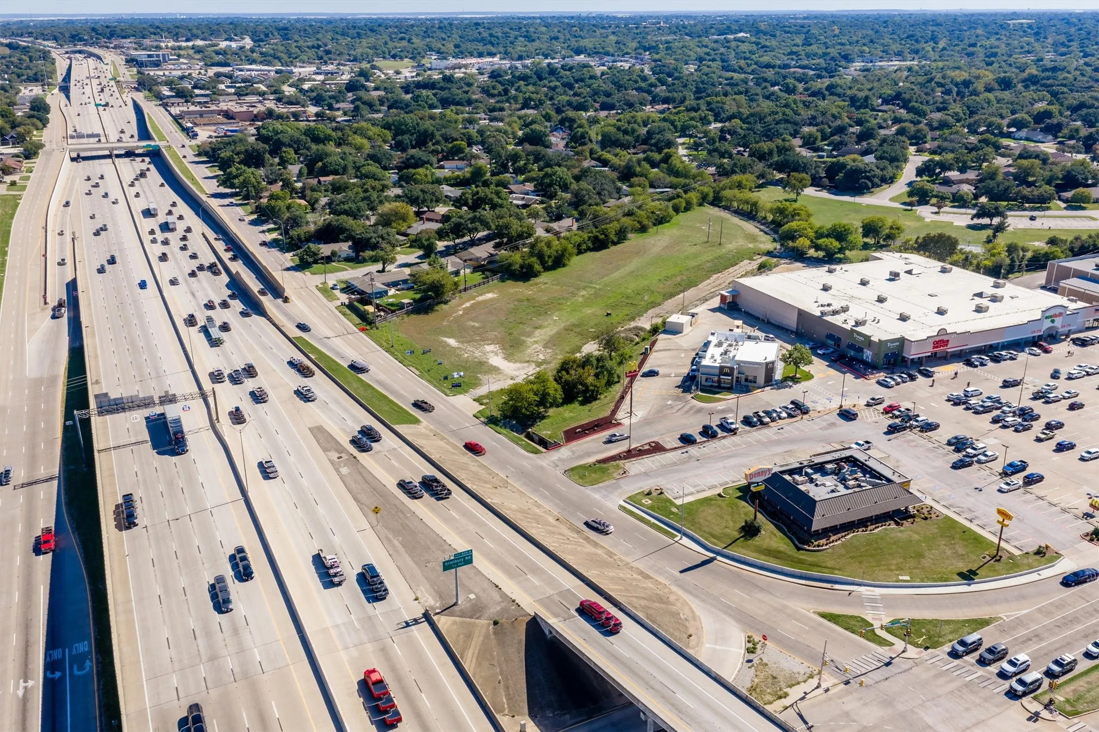 Aerial perspective of a multi-lane highway corridor featuring paved access roads, proximity to commercial retail centers, and established infrastructure