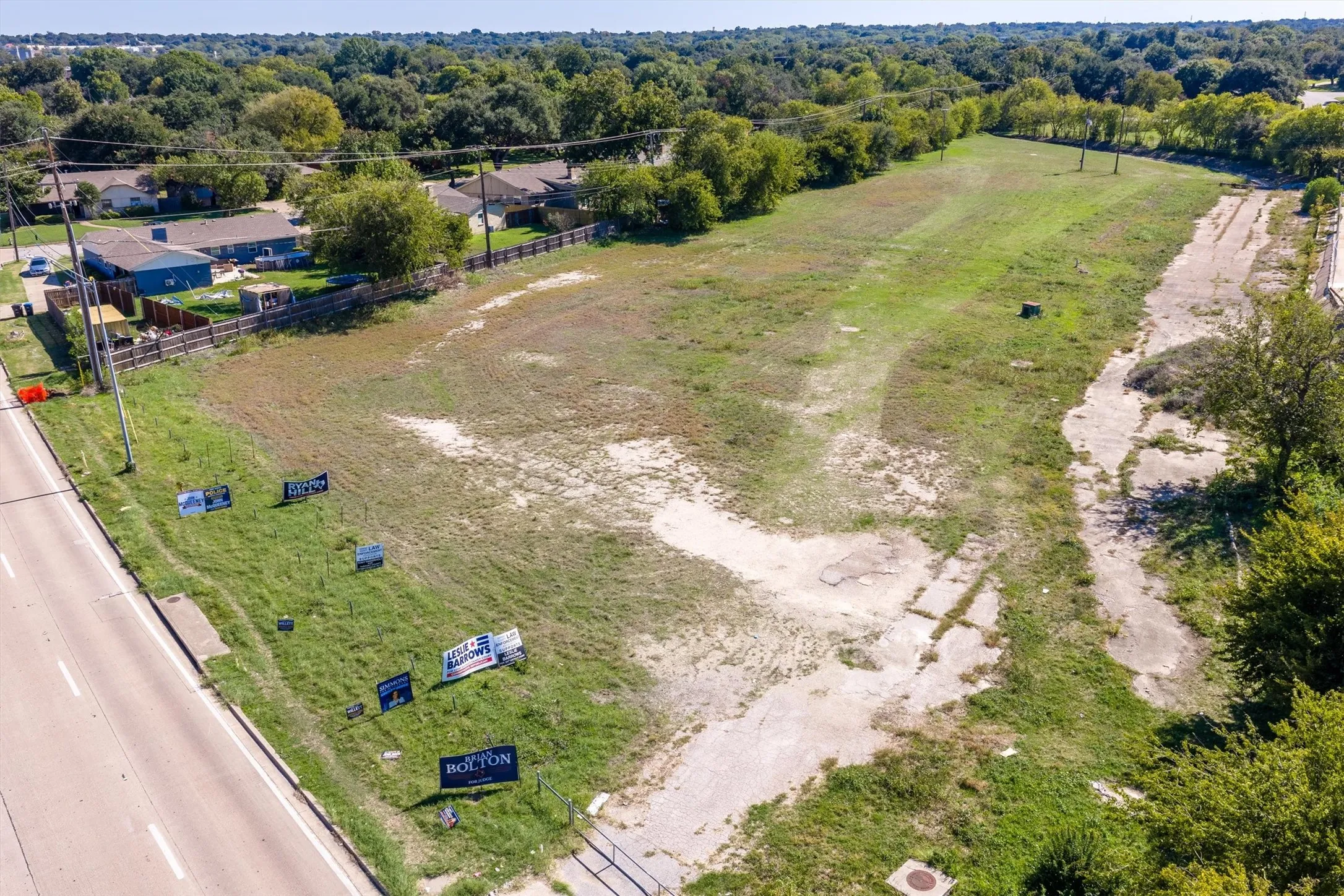 Expansive parcel of open land featuring direct road frontage, mature perimeter trees, and varied topography