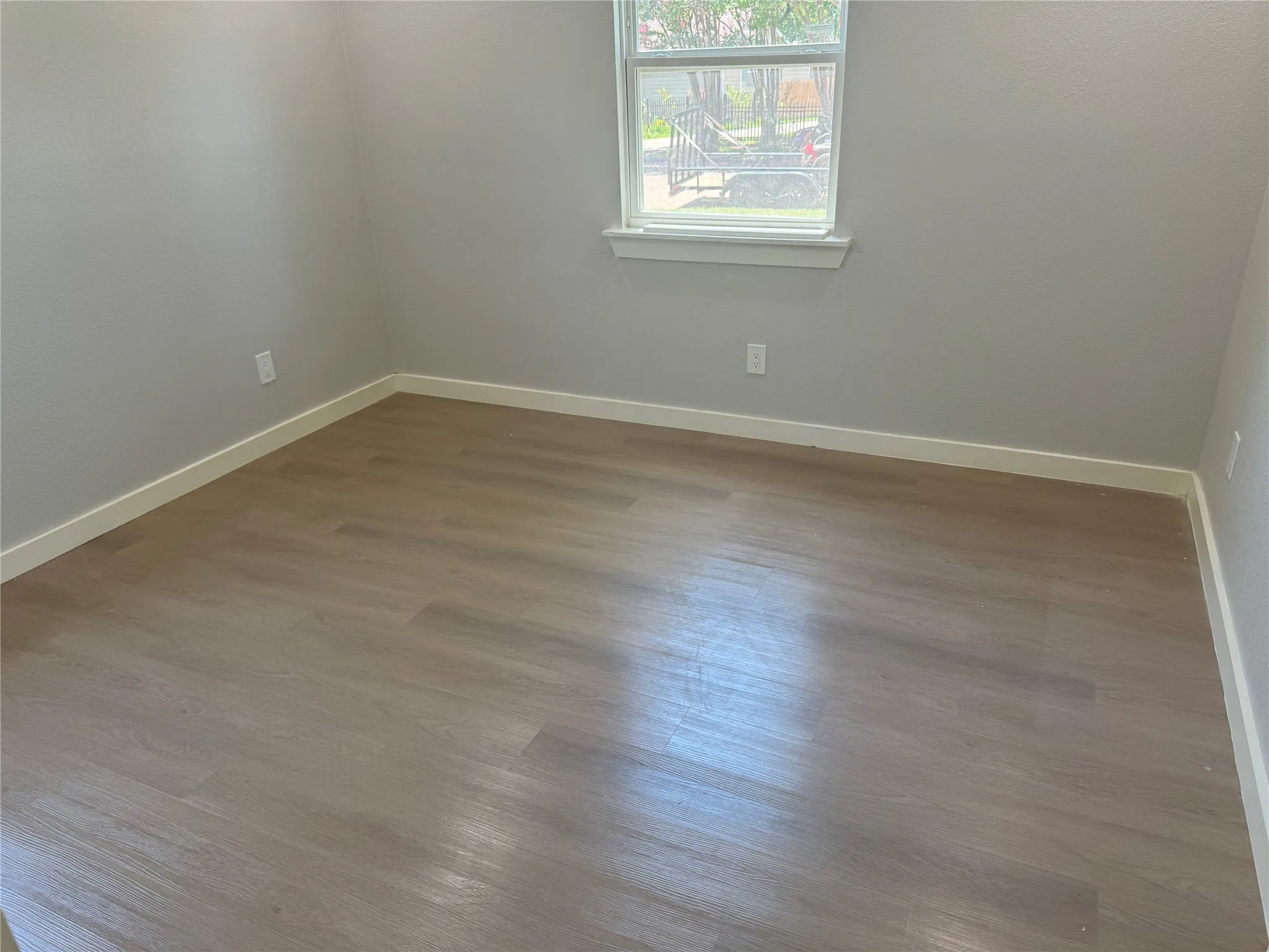 Room featuring wood-finish flooring, neutral paint palette, and a single-pane window with a sill