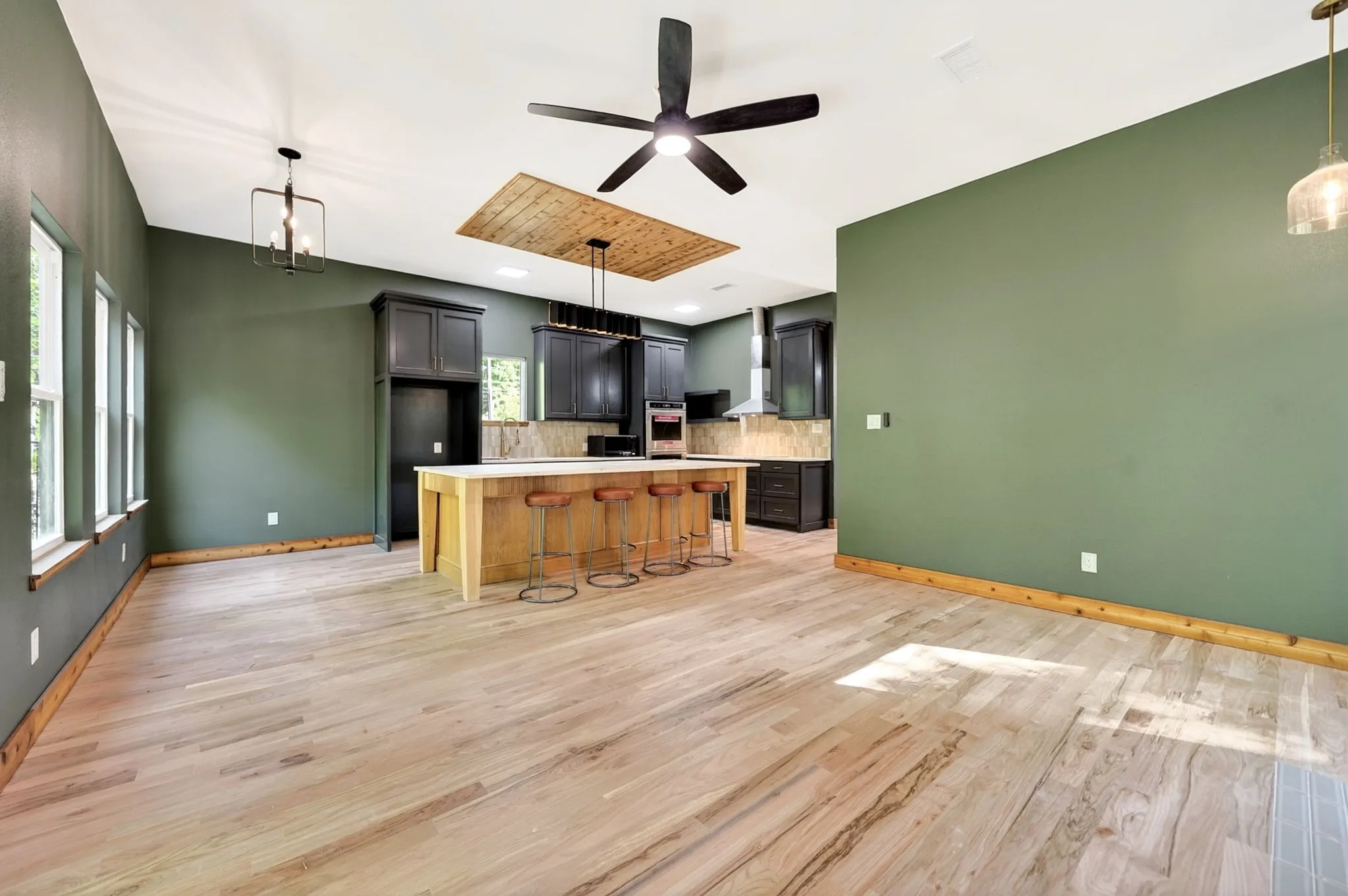 Kitchen featuring a wood-topped center island, custom dark cabinetry, wood-finish flooring, vaulted ceiling with wood paneling inlay, and integrated stainless steel appliances