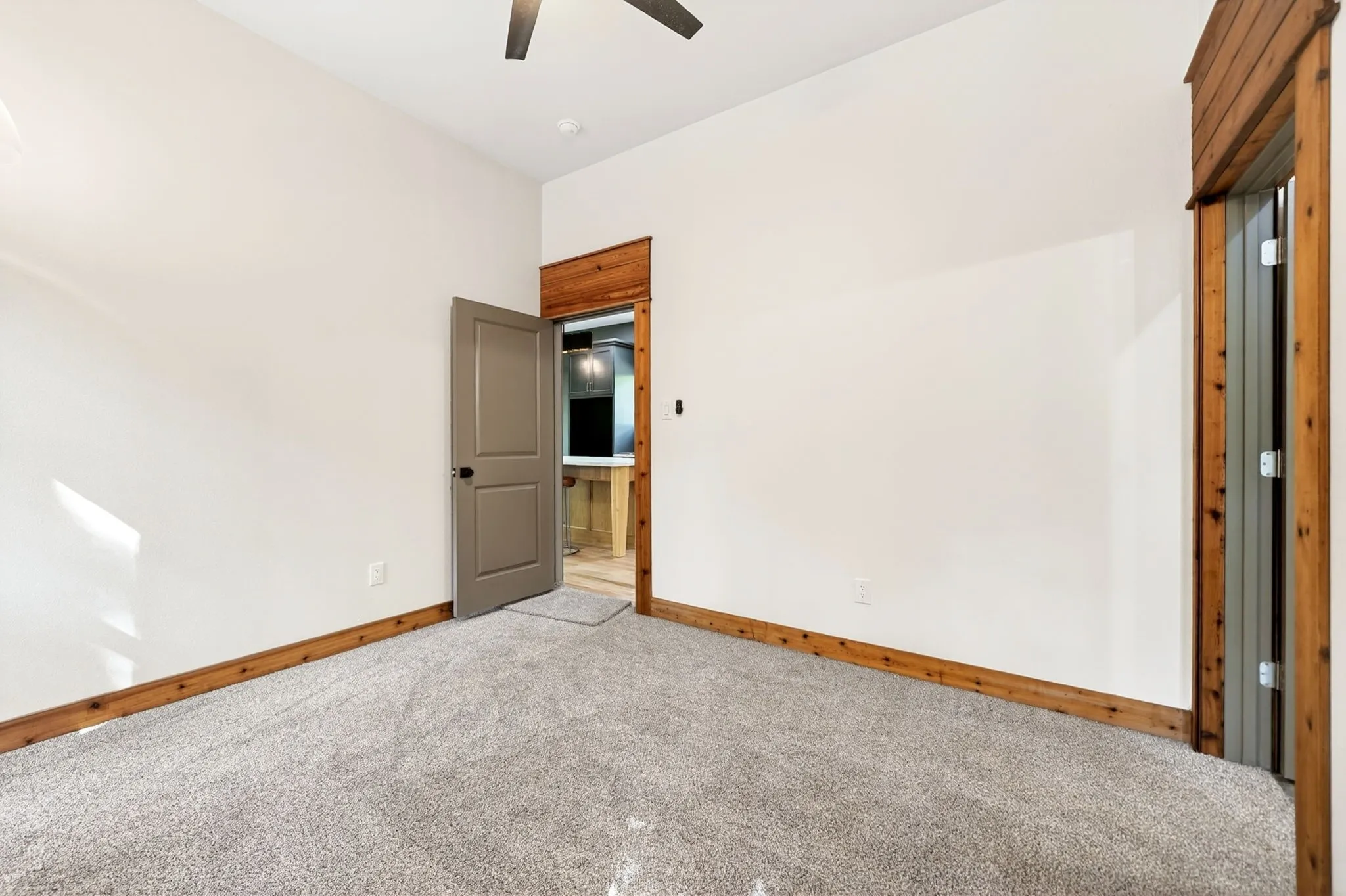 Neutral-toned carpeting, natural wood-trimmed doorways, solid-core interior door, and ceiling fan