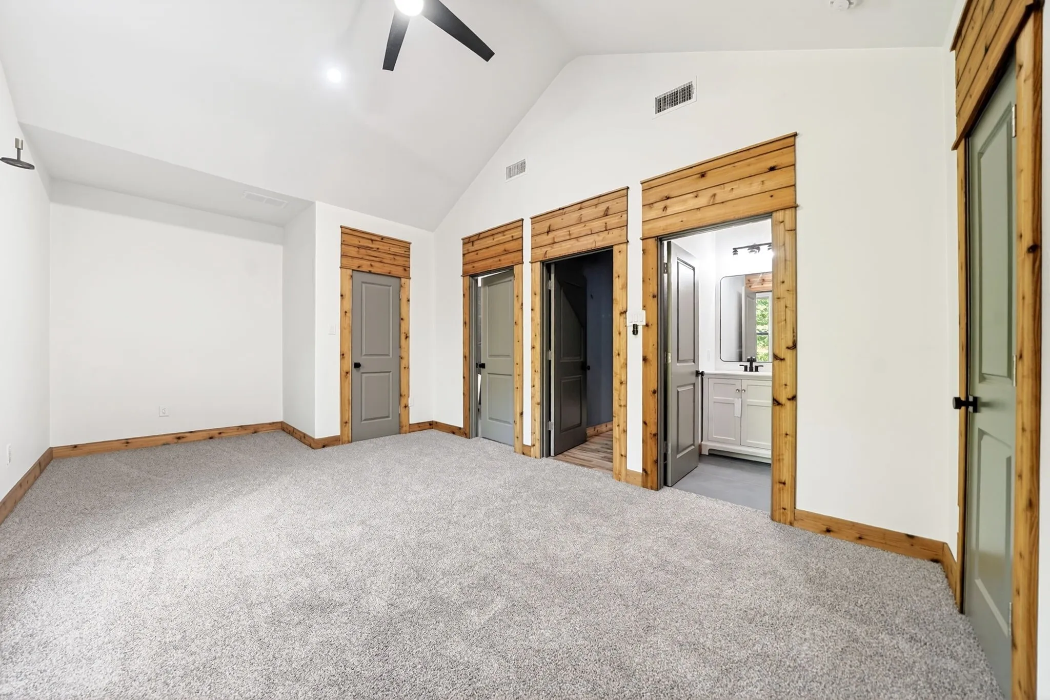 Vaulted ceilings, neutral carpeting, natural wood-finish trim, paneled interior doors, and built-in ceiling fan
