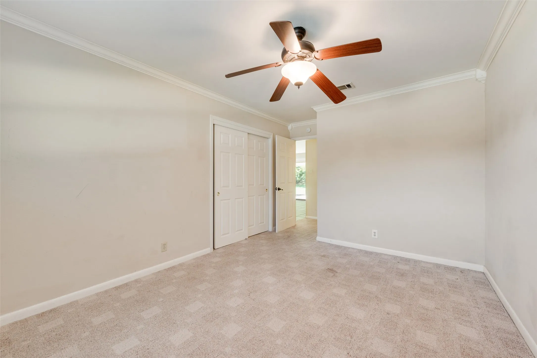 Room featuring neutral wall-to-wall carpeting, crown molding, and a central ceiling fan with integrated lighting