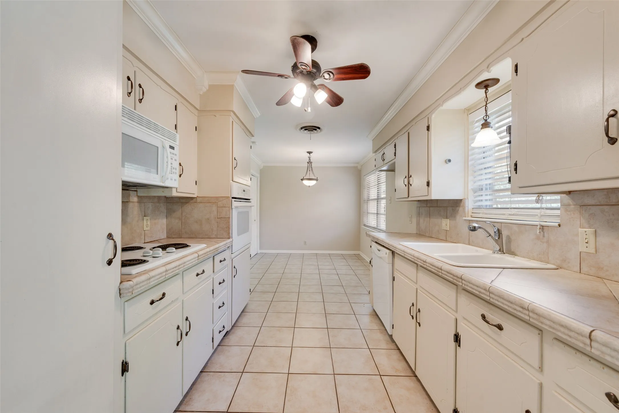 Kitchen featuring white cabinetry, tile countertops, integrated wall oven, tile flooring, and crown molding