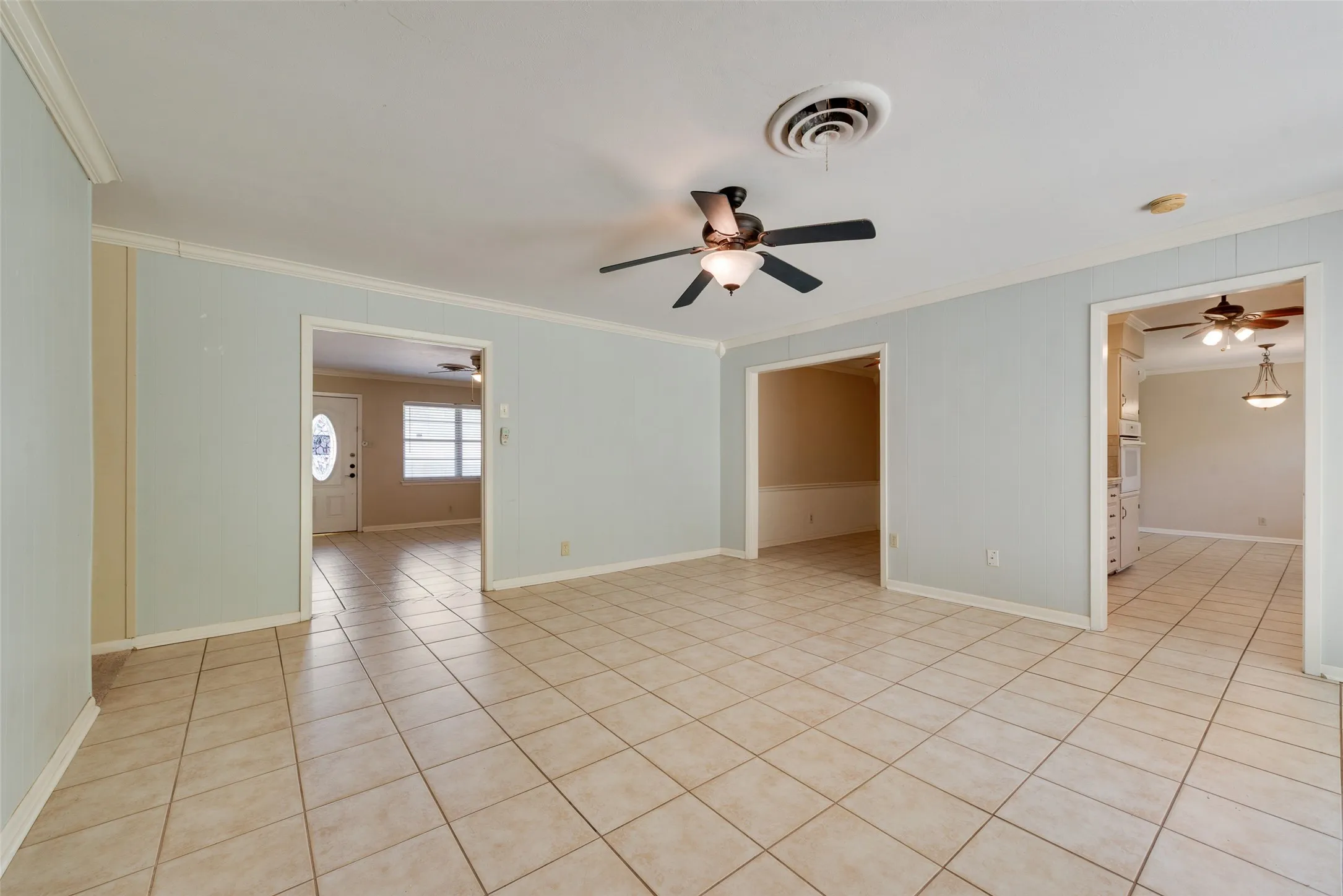 Neutral-toned ceramic tile flooring, ceiling fan with integrated lighting, and multiple cased openings into the Kitchen, the dining room and the living room