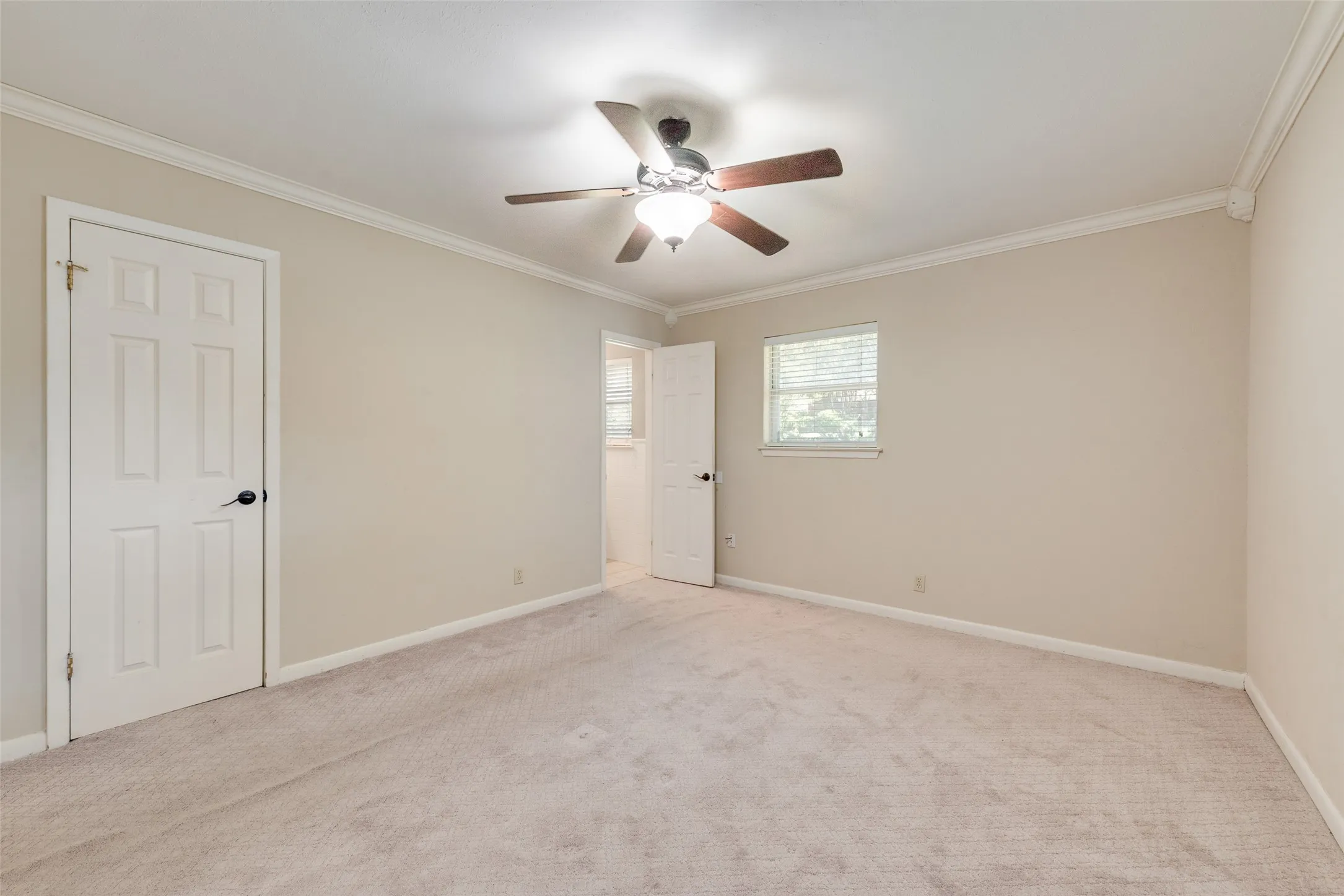 Room featuring neutral wall tones, crown molding, wall-to-wall carpeting, a multi-blade ceiling fan with integrated lighting, and six-panel interior doors