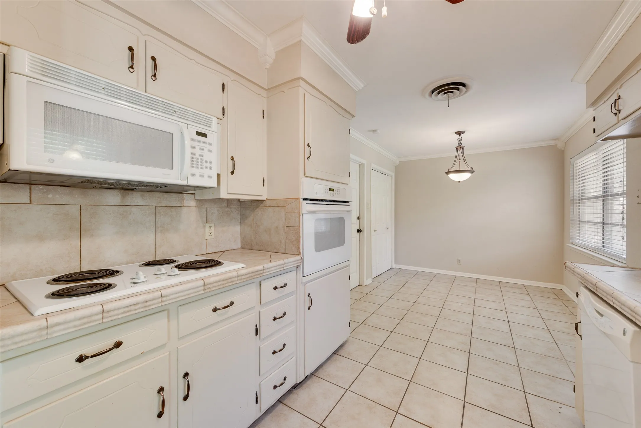 Kitchen featuring light-toned cabinetry, tile countertops with matching tile backsplash, built-in wall oven, and ceramic tile flooring