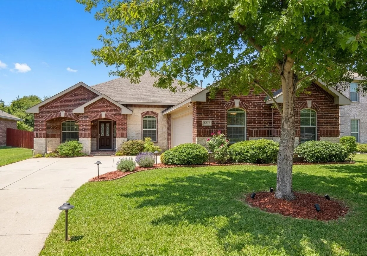 Exterior facade featuring multi-textured brick and stone masonry, arched window detailing, a covered entryway, and a concrete​​‌​​​​‌​​‌‌​‌‌​​​‌‌​‌​‌​‌​​​‌​​ driveway