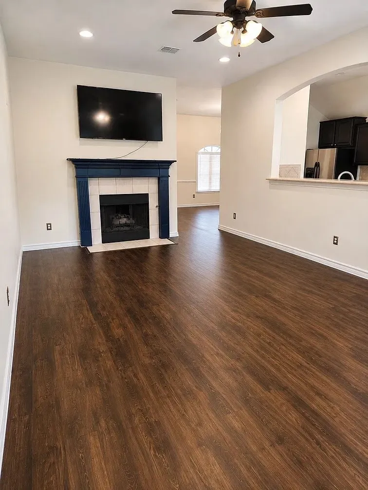 Living area featuring dark wood-finish flooring, recessed lighting, and a fireplace with a mantel and tiled surround