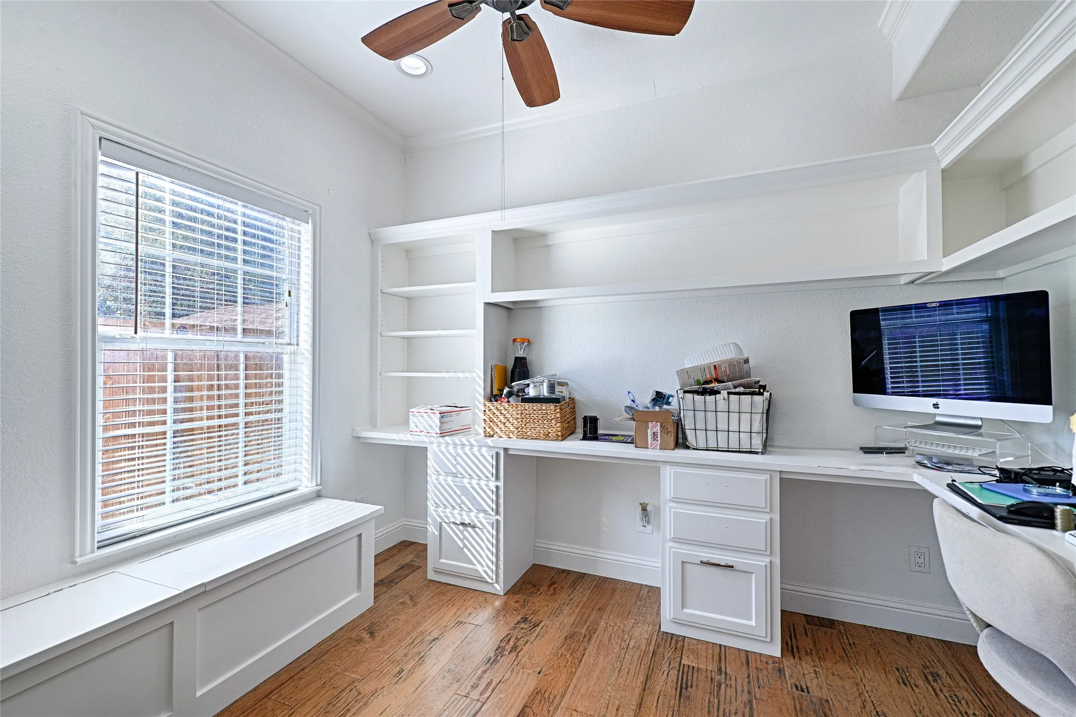Custom-looking built-in desk, cabinetry, shelving, natural light, and ceiling fan. A valuable feature for remote work or business use.