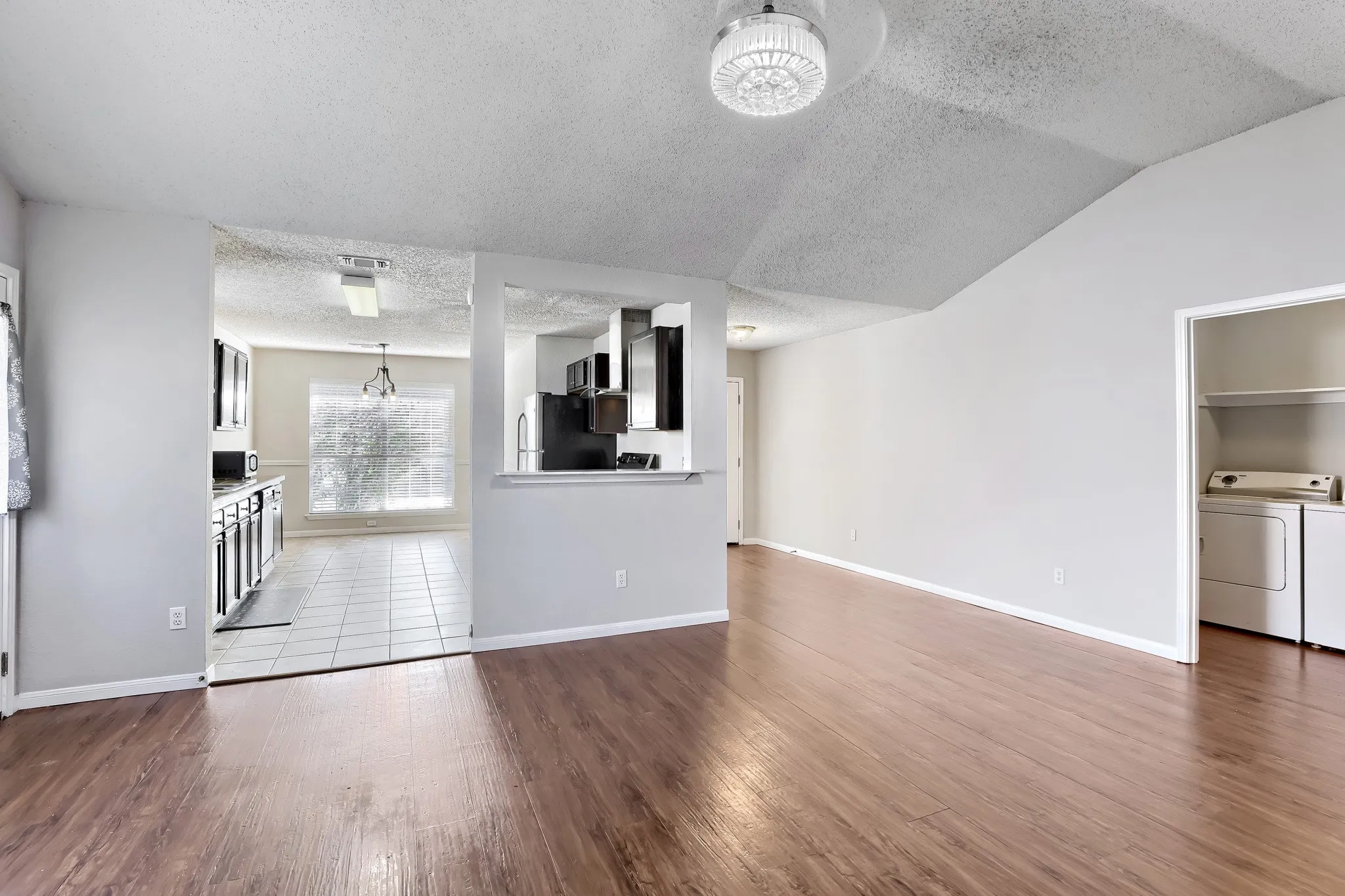 Vaulted ceilings, wood-finish flooring, kitchen pass-through window, and dedicated laundry area