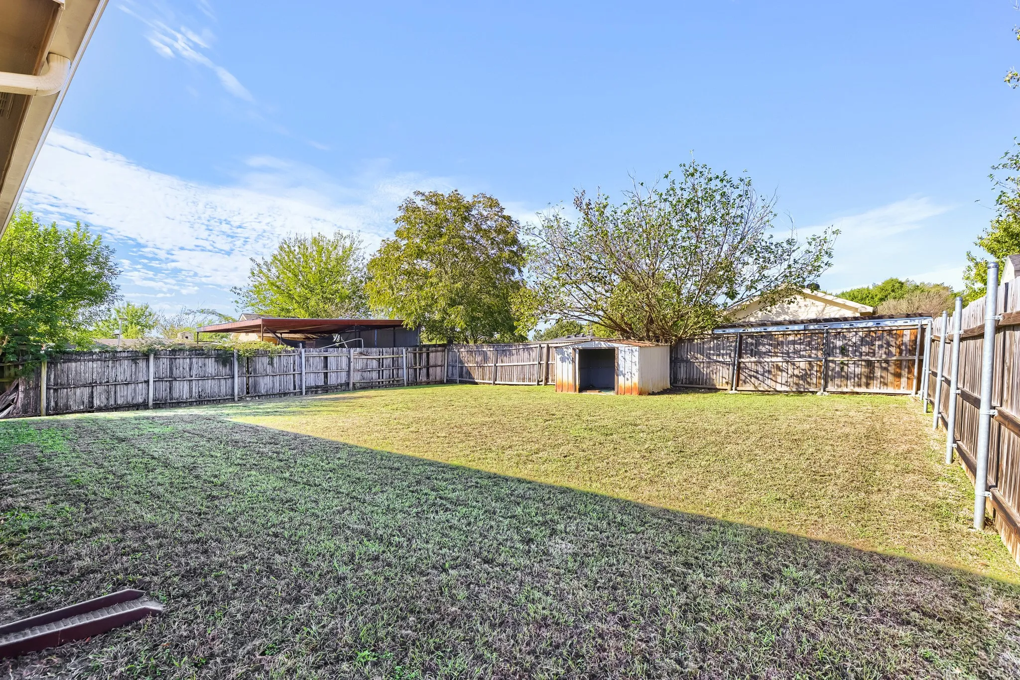 Expansive backyard featuring a lawn, full-perimeter wood fencing, and a detached storage structure