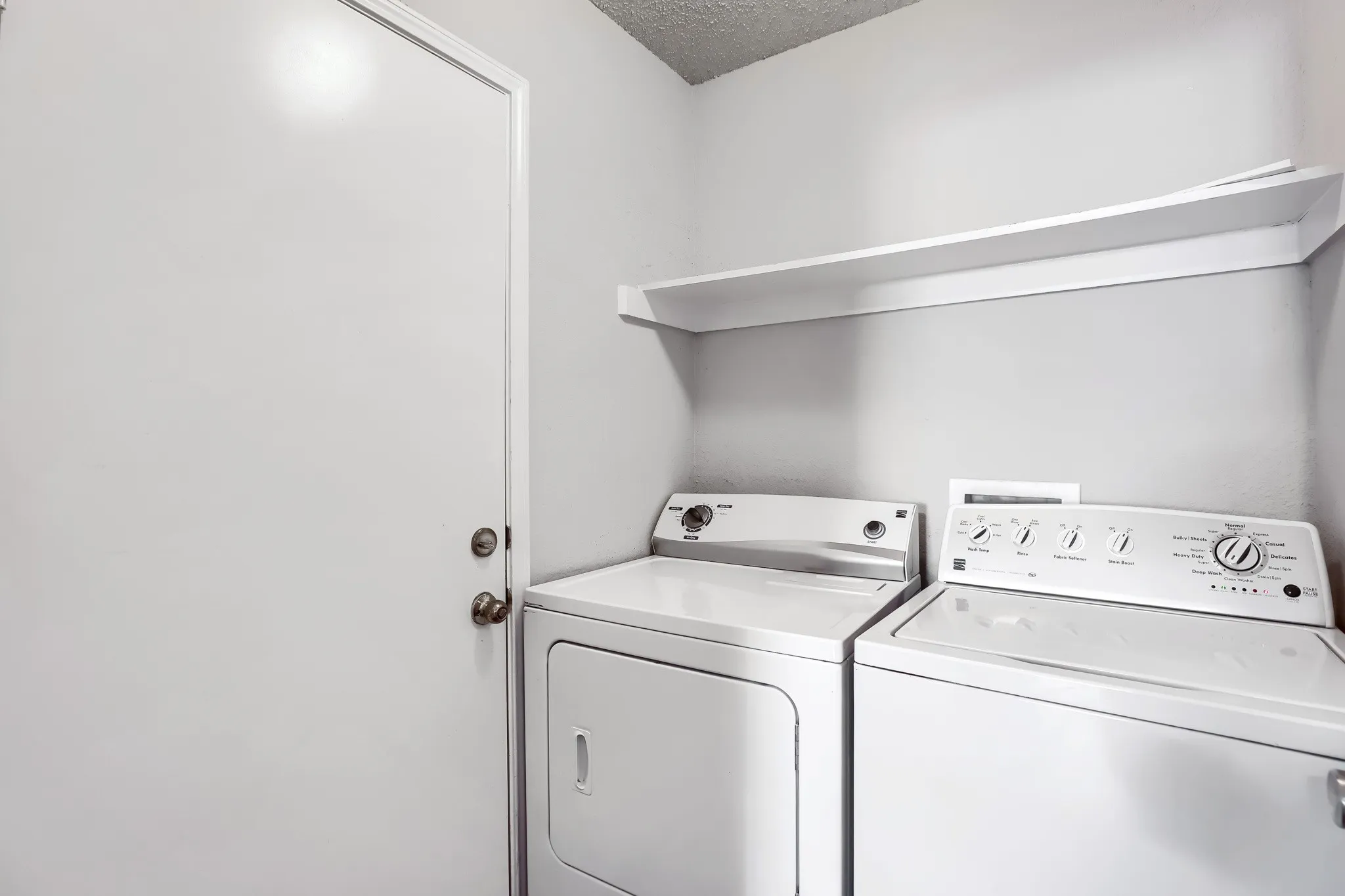 Utility area featuring a wall-mounted shelving unit and a door with metallic hardware