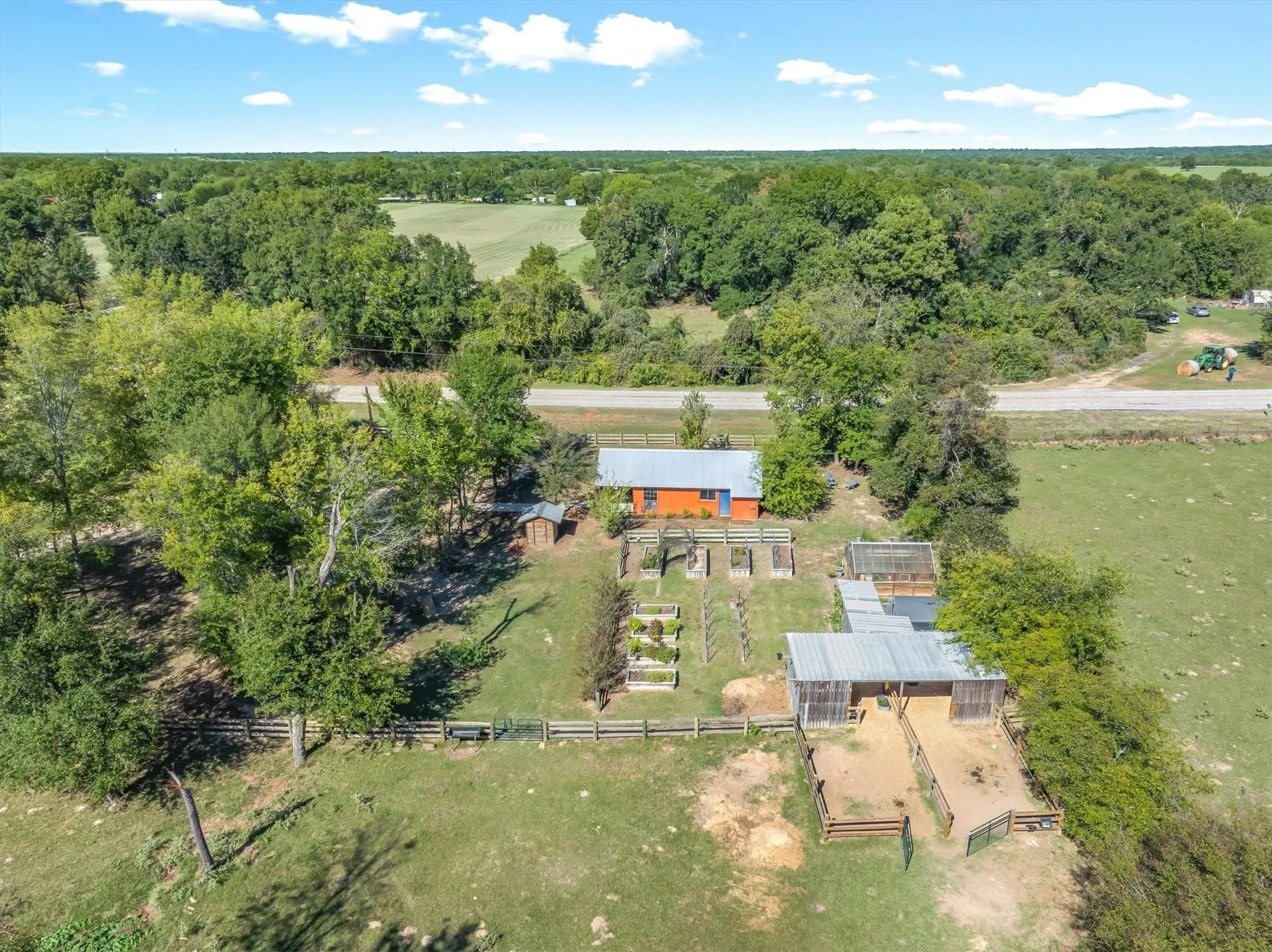 Great view of the raised bed gardens, greenhouse and barn with stalls.