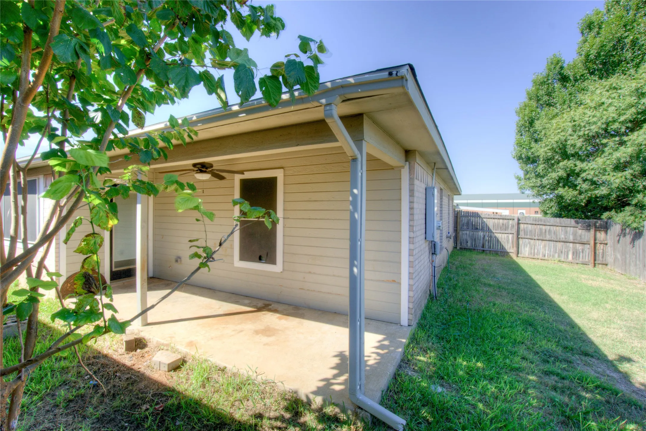 Covered concrete patio featuring horizontal siding, a built-in ceiling fan, and fenced outdoor space