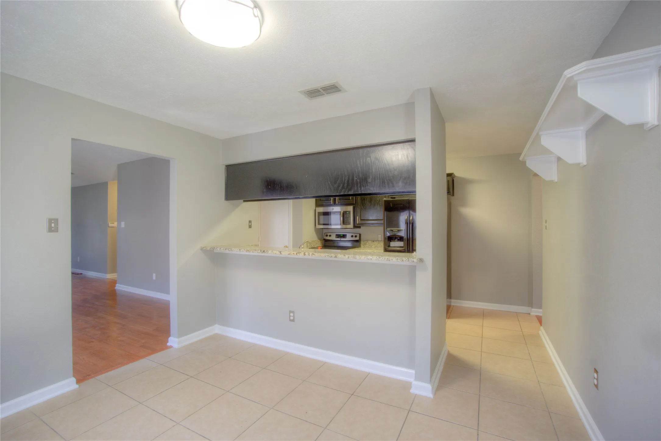 Kitchen featuring a stone-look breakfast bar, built-in shelving, tile flooring, and integrated overhead lighting