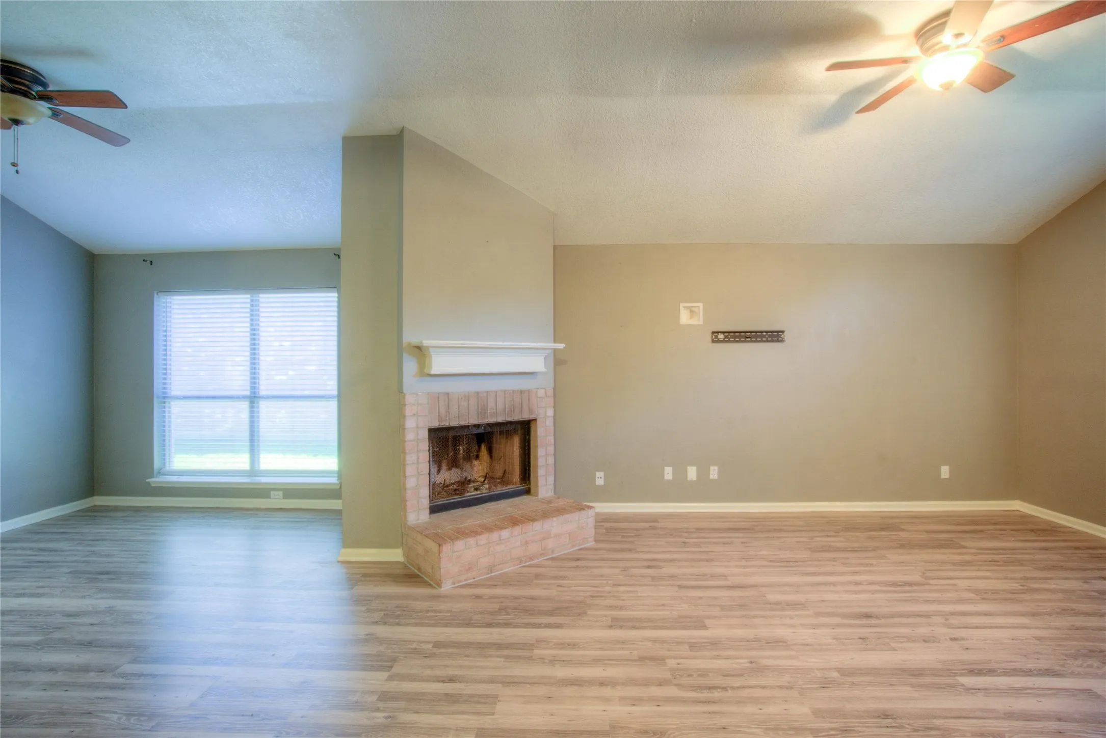 Vaulted ceilings, wood-finish flooring, masonry fireplace with a mantel, and two ceiling fans