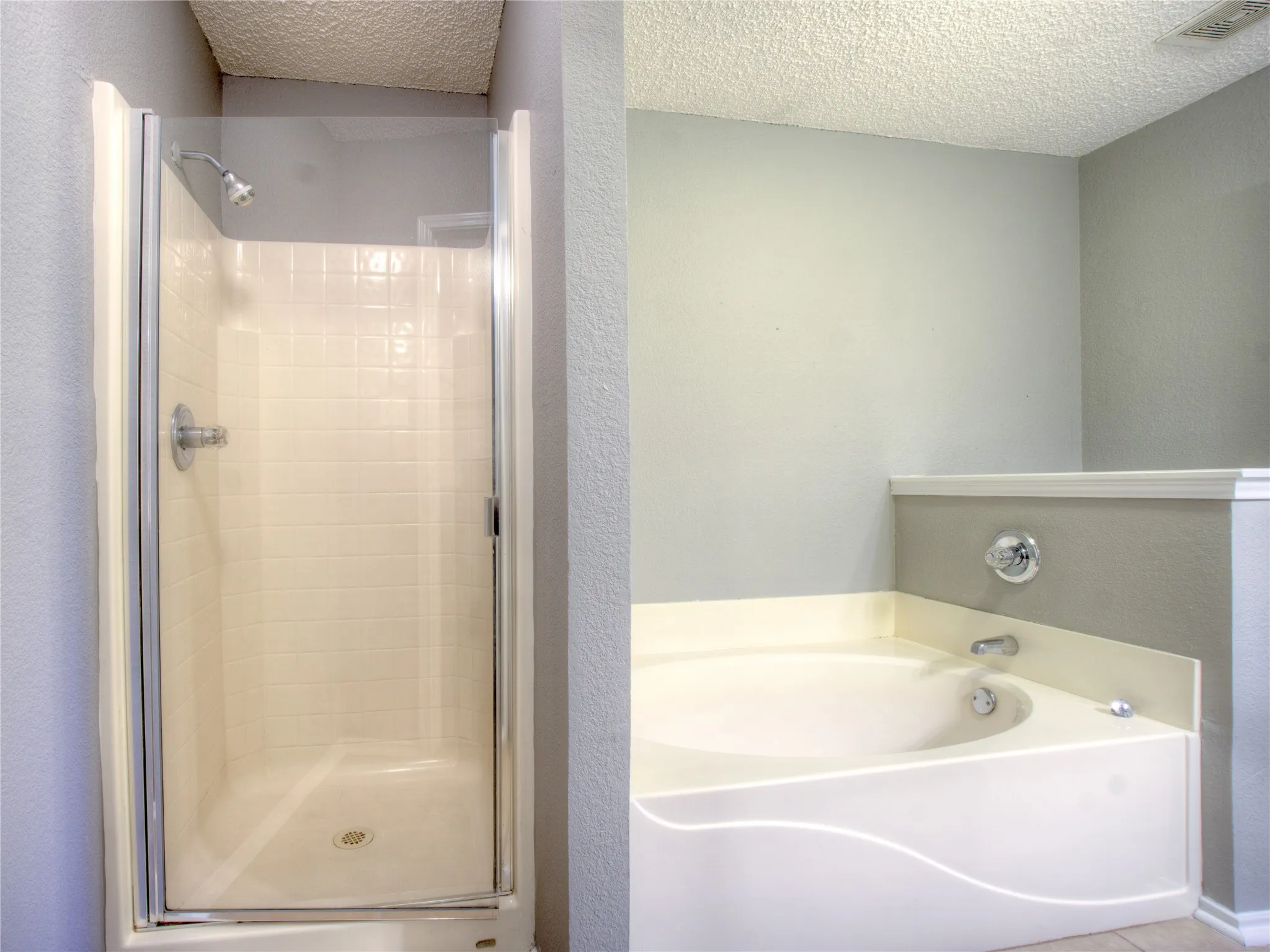 Walk-in shower featuring a glass door and tiled surround, accompanied by a built-in soaking tub with a deck-mounted faucet