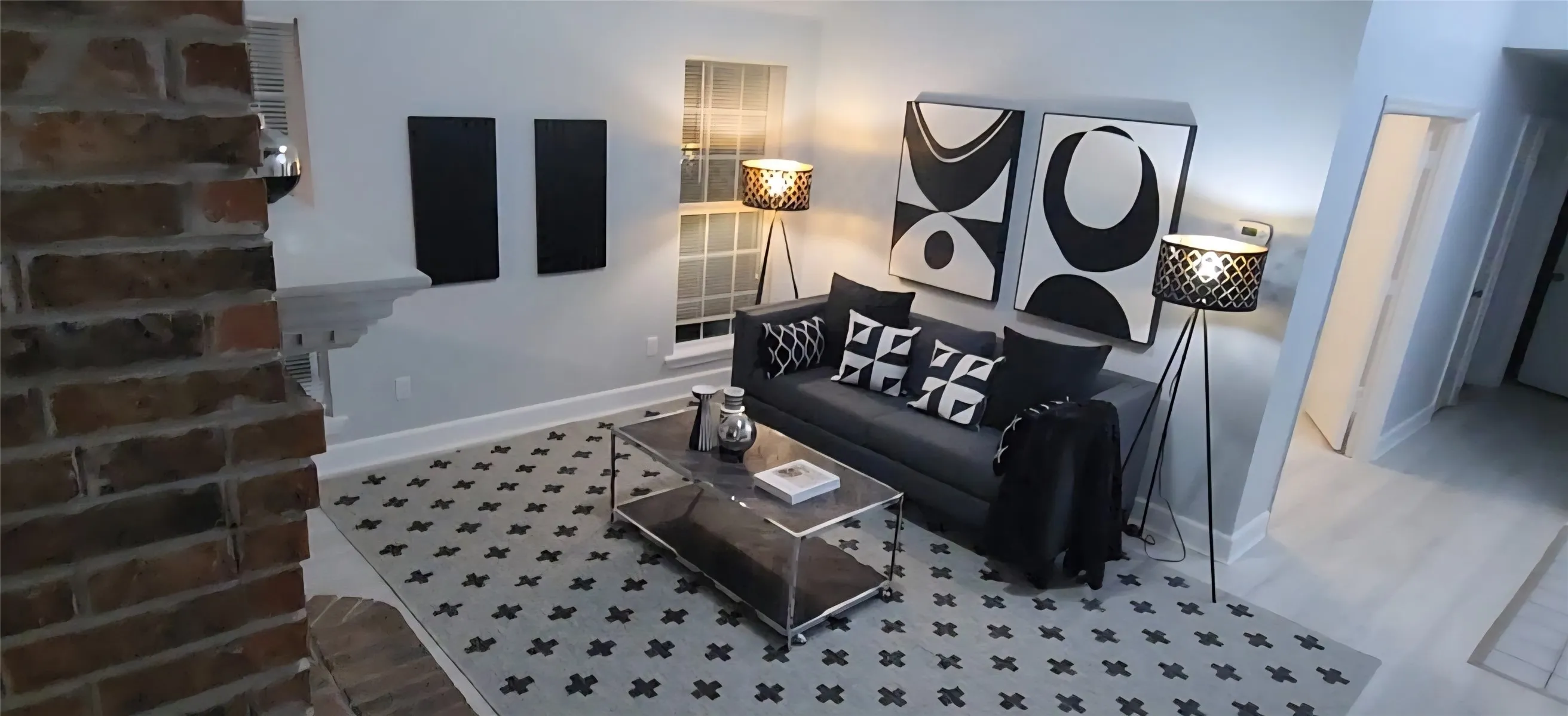 Living area featuring a floor-to-ceiling brick fireplace, neutral wall tones, multi-pane windows, and light-toned flooring
