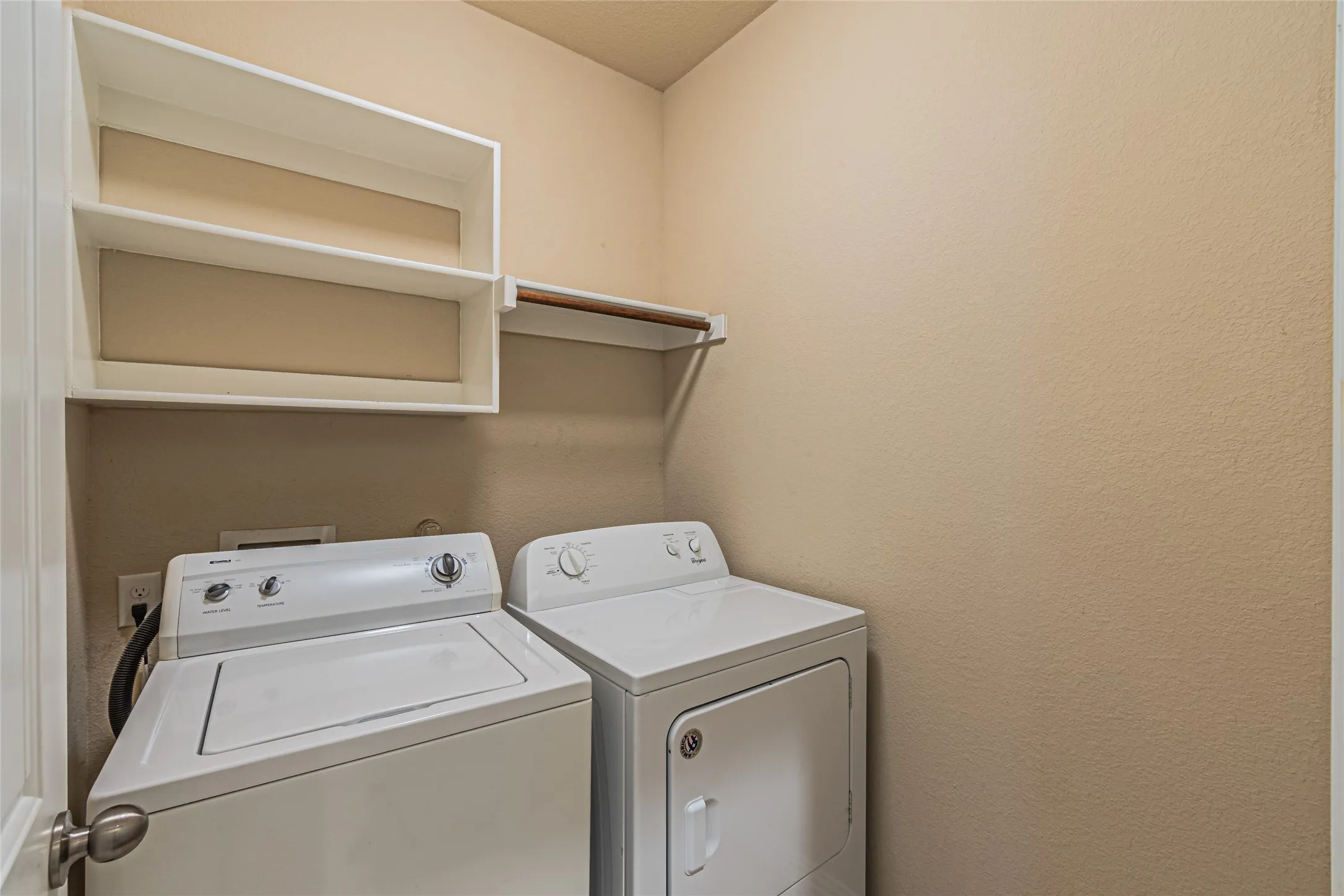 Utility space featuring white open-frame wall shelving and a built-in horizontal hanging rod