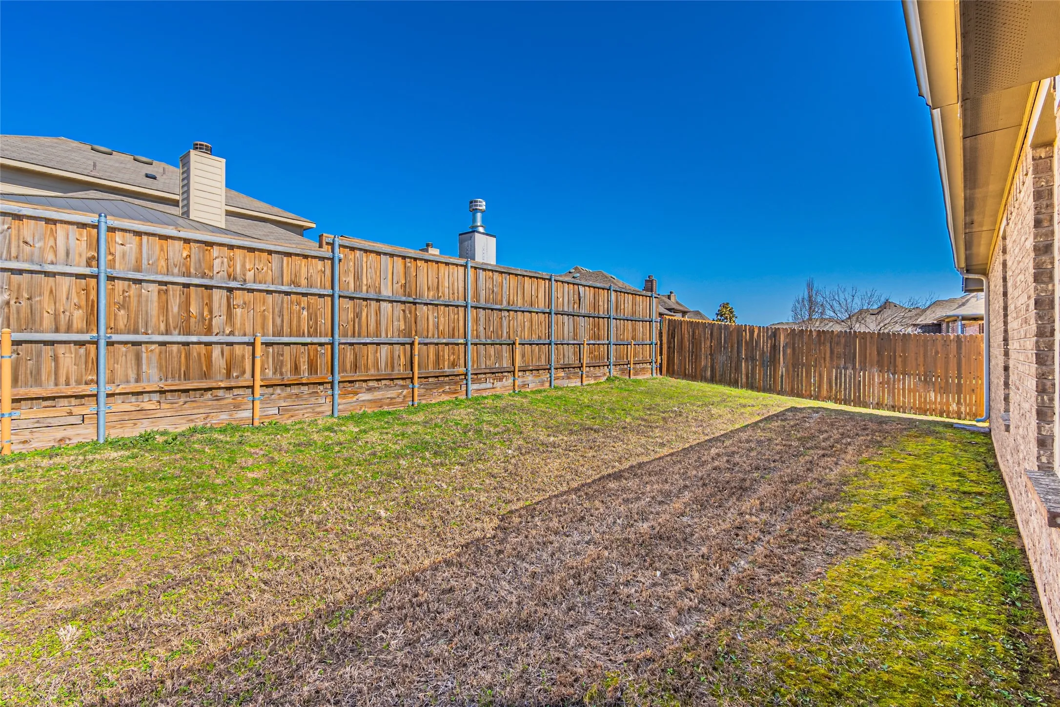 Backyard featuring a full-perimeter wood privacy fence and exterior brick siding