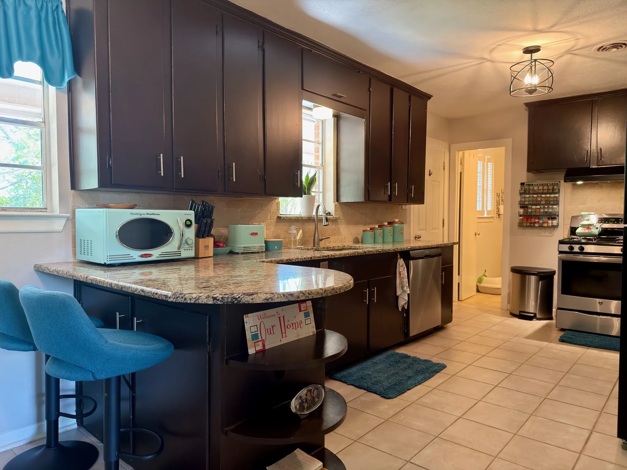 15x12 Kitchen featuring dark cabinetry, stone countertops, integrated peninsula seating, stainless steel appliances, and tile flooring