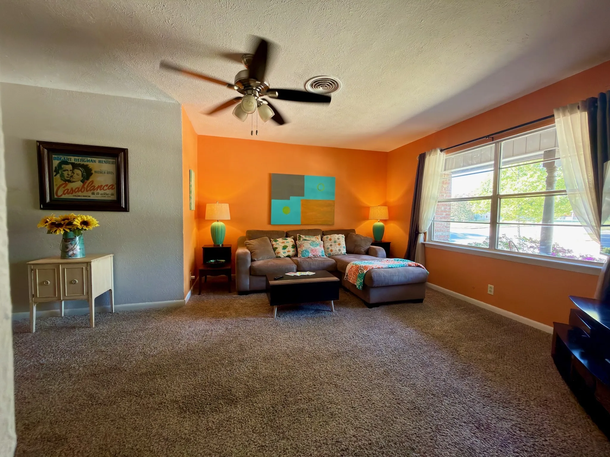 18x14 Living area featuring wall-to-wall carpeting, a multi-blade ceiling fan, and large windows with natural light