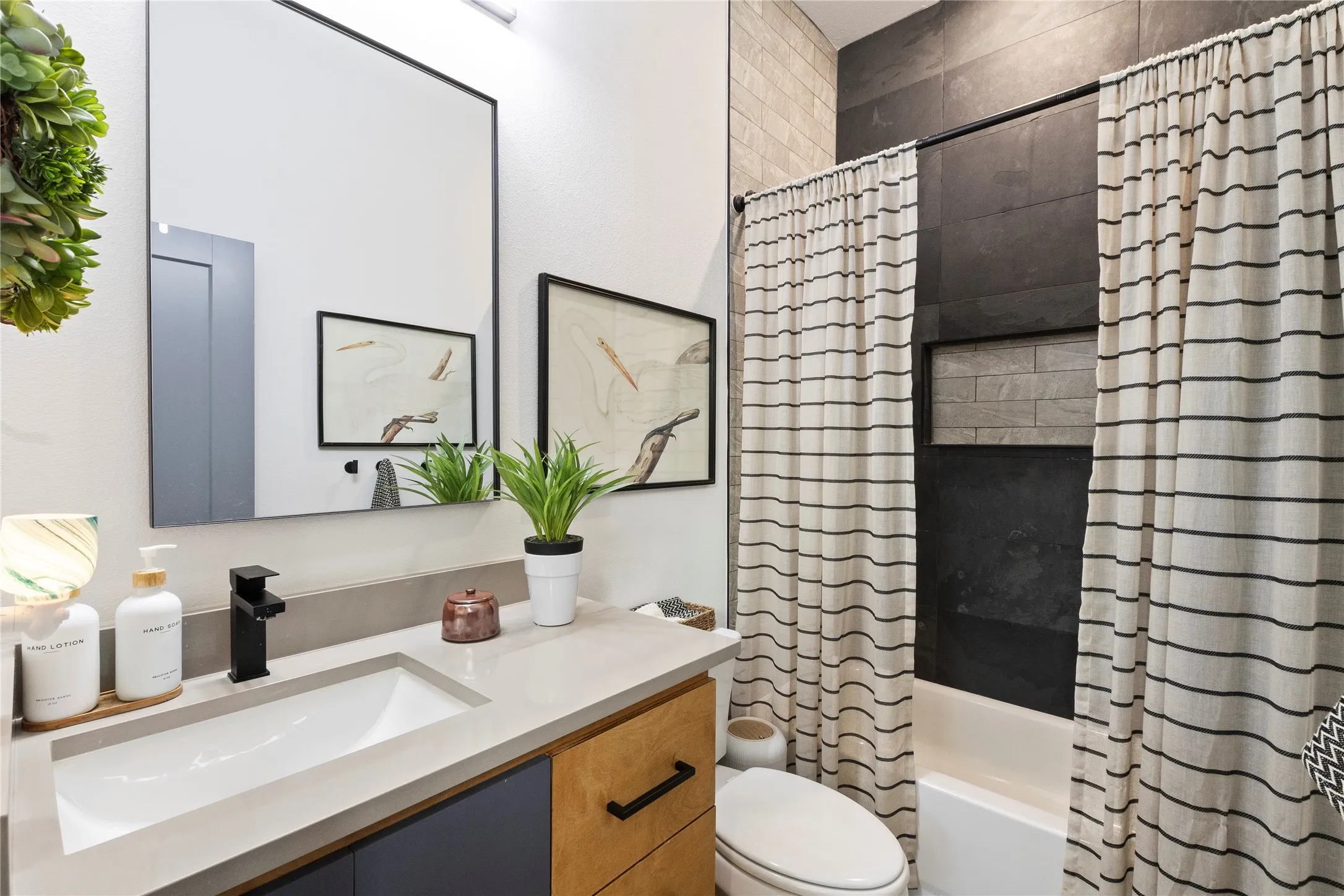 Modern vanity with a light-toned solid surface countertop, matte black faucet, rectangular undermount sink, and dual-tone cabinetry featuring black hardware