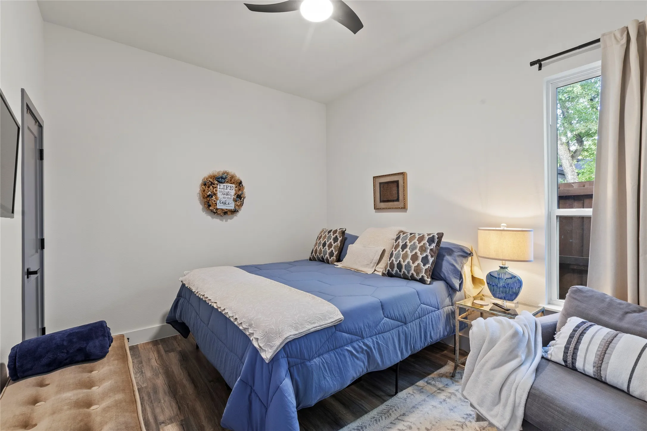 Interior space featuring wood-finish flooring, high ceilings, a contemporary ceiling fan, and a single-hung window with a neutral curtain rod