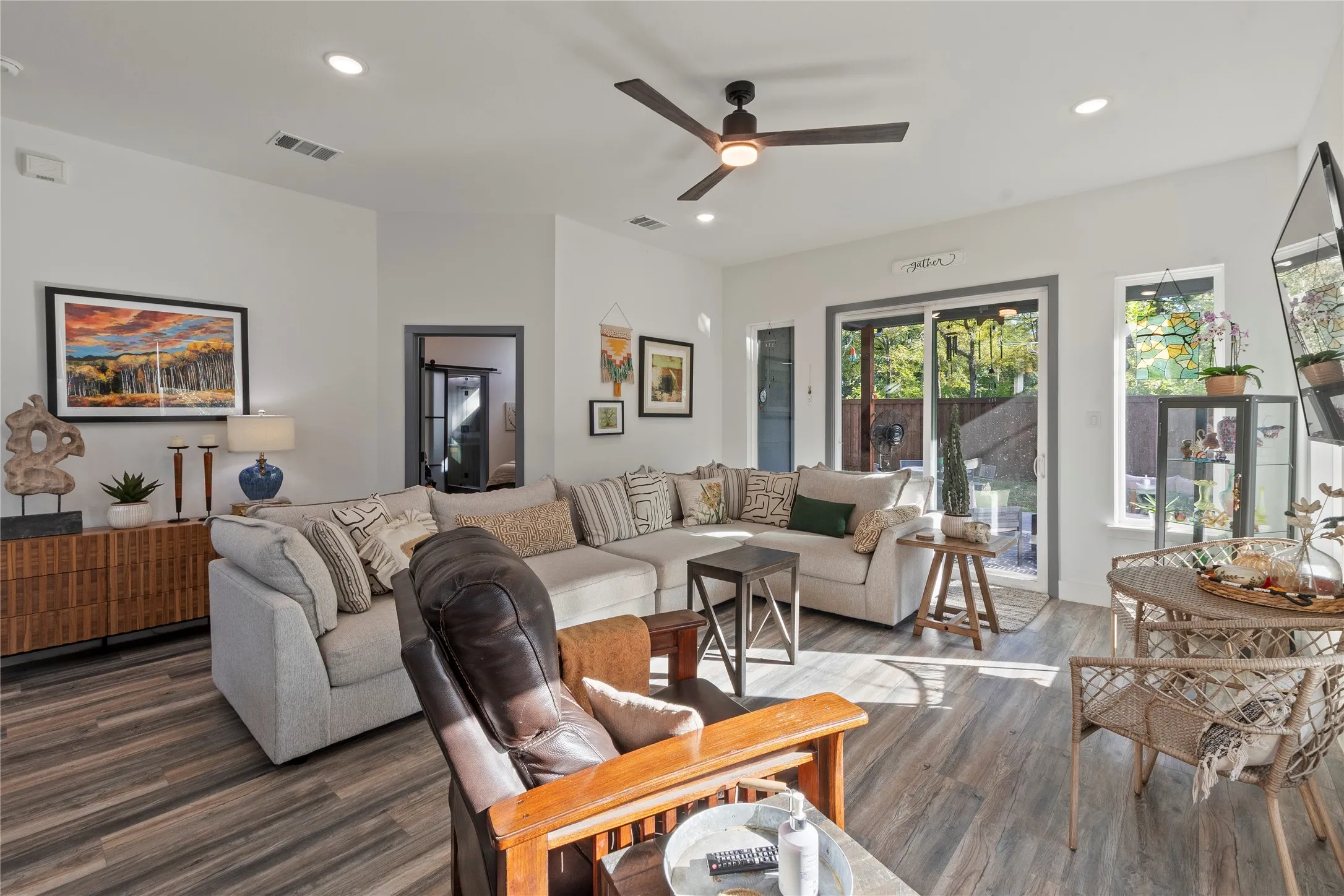 Living area featuring wood-finish flooring, recessed lighting, a ceiling fan with integrated lighting, and a sliding glass door