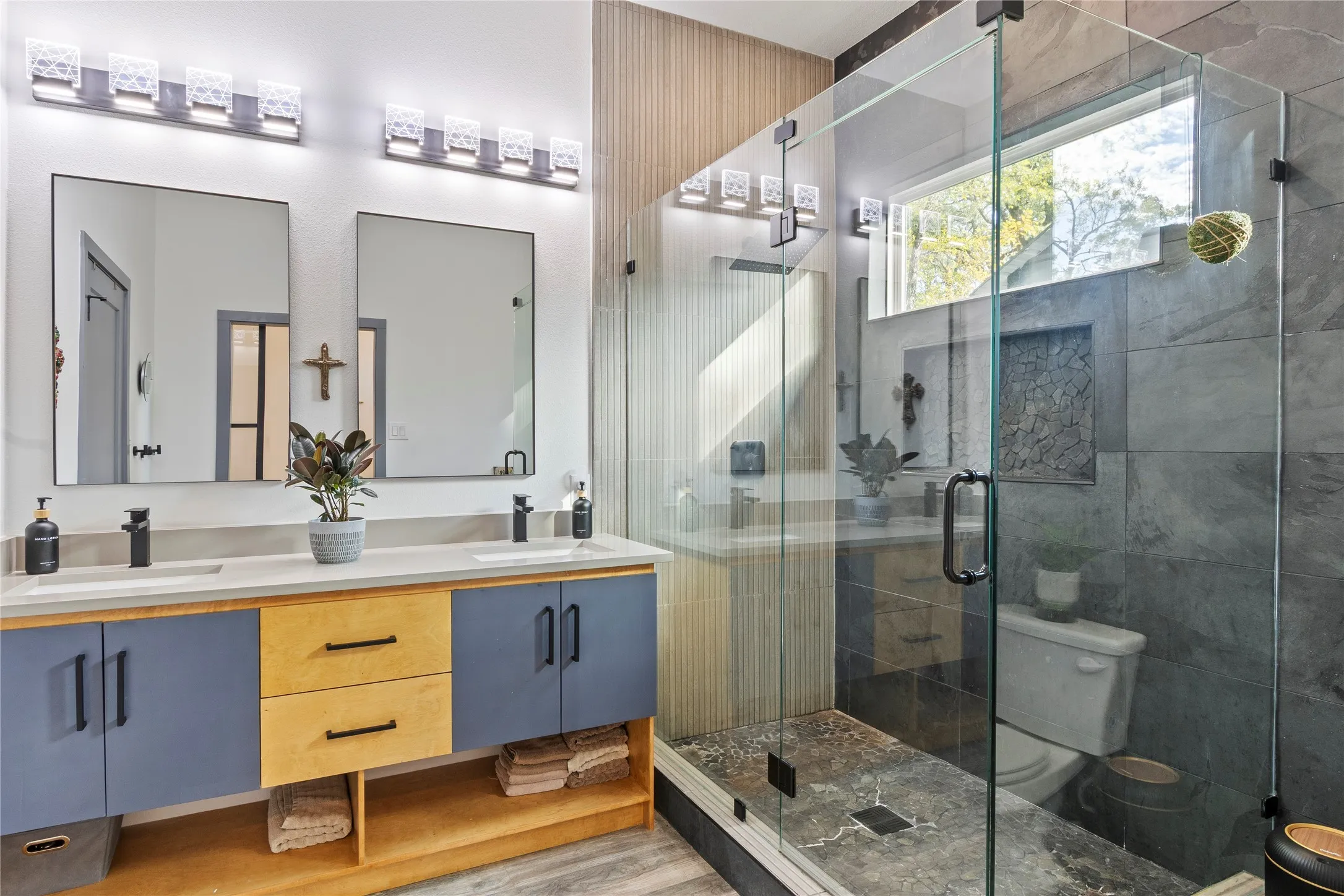Dual-sink vanity featuring a light-toned countertop, custom two-tone cabinetry, and matte black hardware