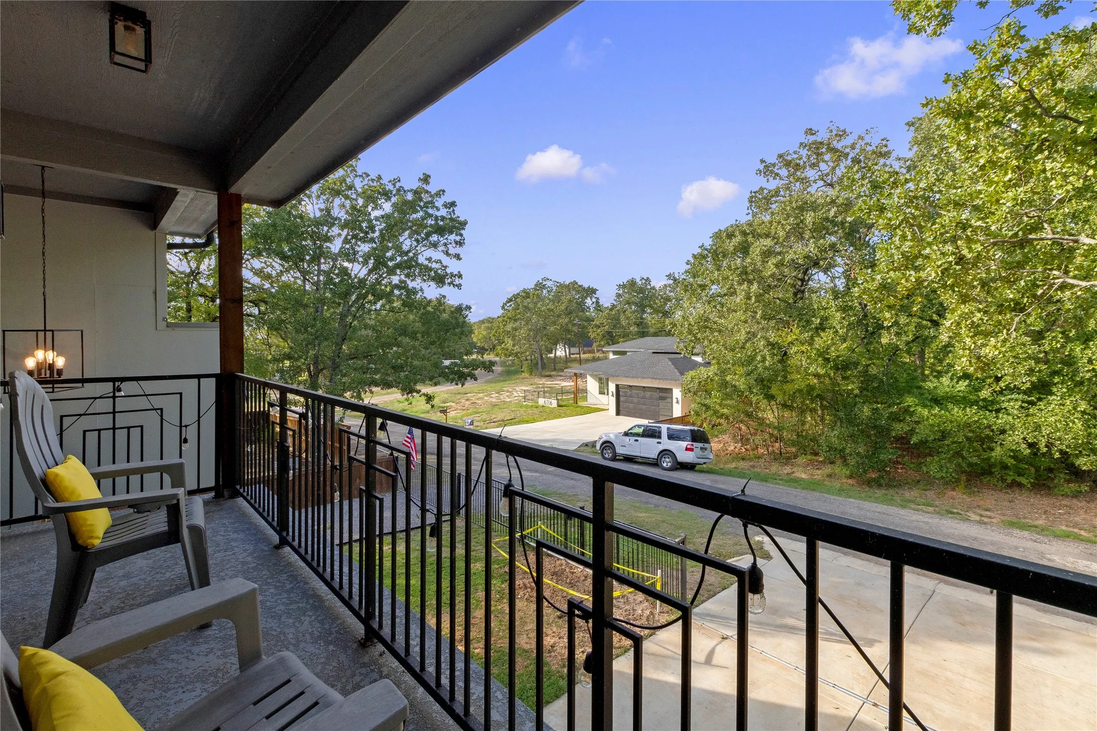 Covered balcony featuring concrete flooring, black metal railing, and an attached overhead pendant light fixture
