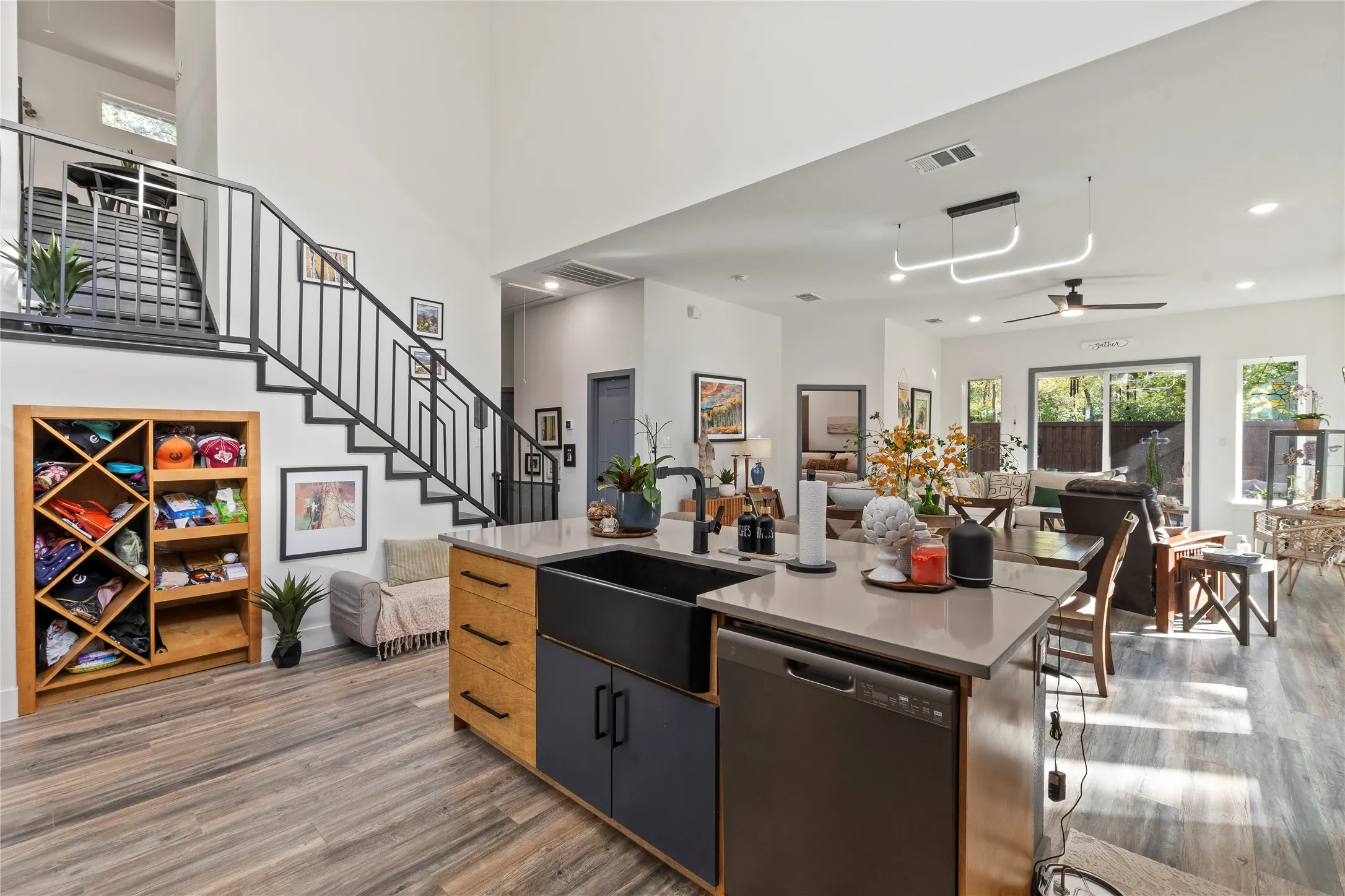 Kitchen featuring an island with a quartz countertop, black farmhouse-style sink, and dual-toned cabinetry