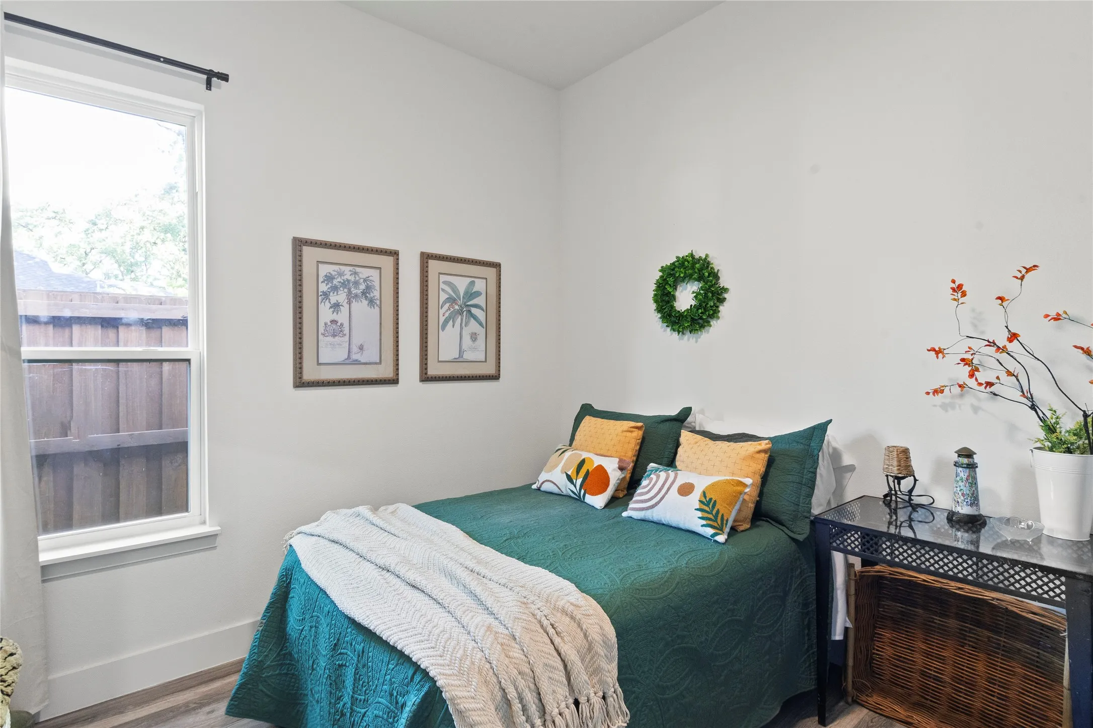 Neutral-toned room featuring a single-hung window with a dark metal curtain rod and wood-finish flooring
