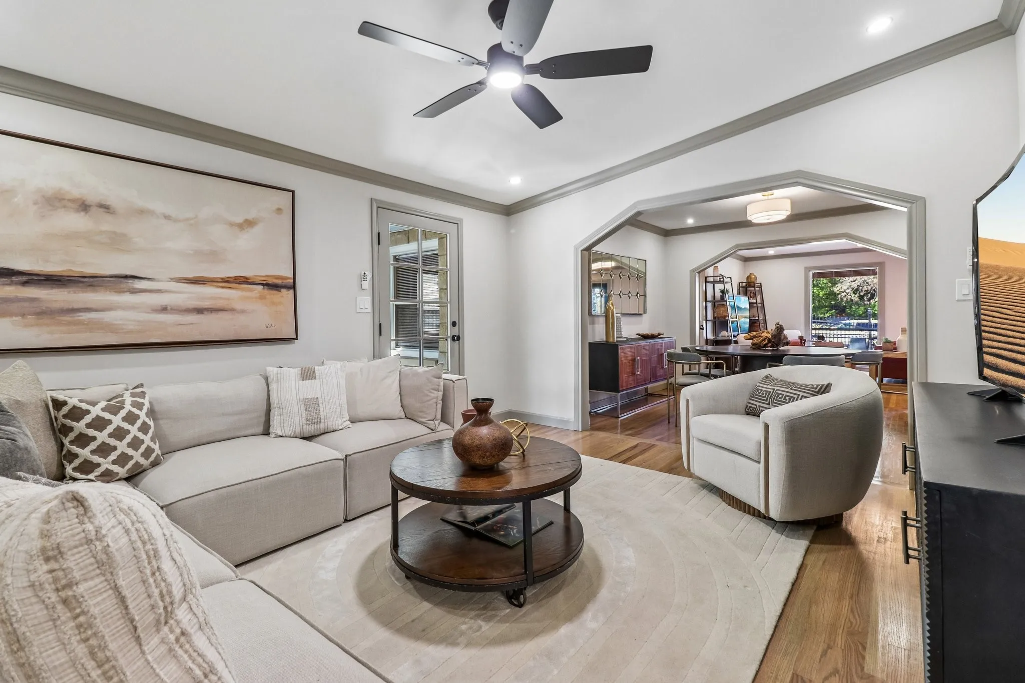 Recessed lighting, crown molding, wood-finish flooring, a ceiling fan with integrated lighting, and an arched entryway