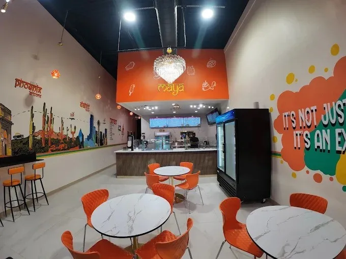 High-ceiling interior space featuring a service counter with a neutral-toned base, integrated crystal-style chandelier lighting, recessed overhead lighting, and painted wall murals