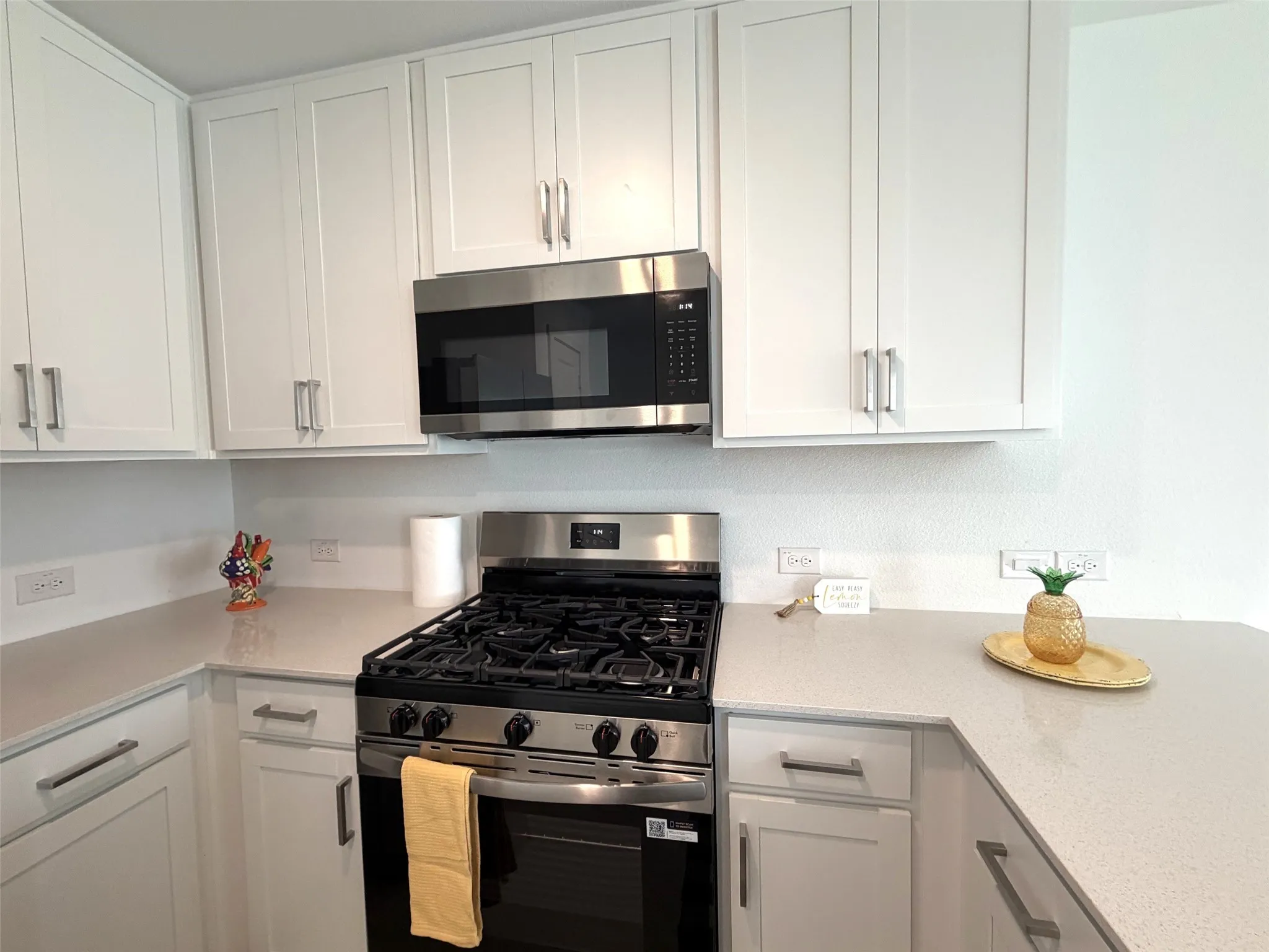 White shaker-style cabinetry, and stainless-steel gas range and built-in microwave