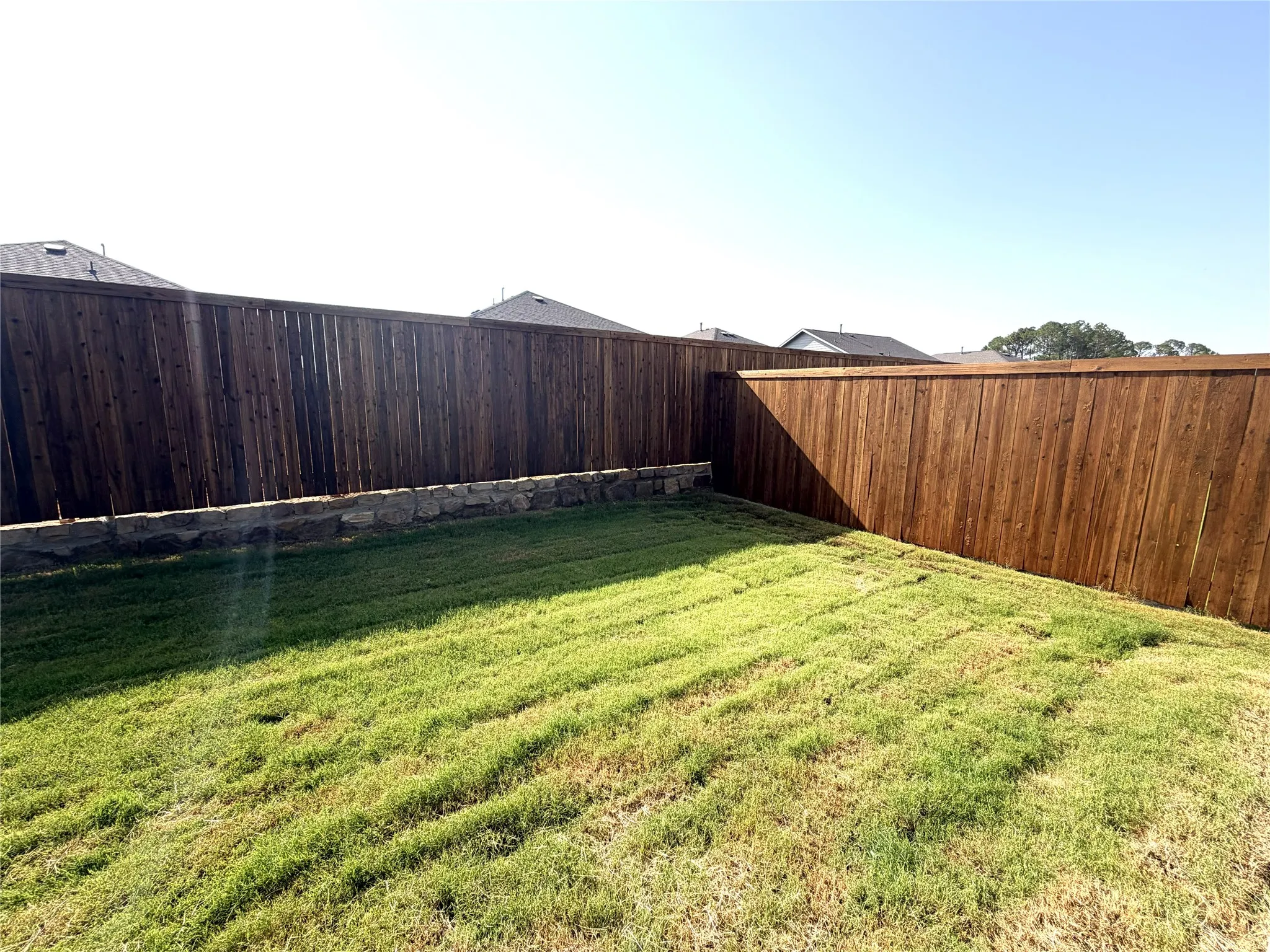 Backyard featuring a wood privacy fence and a stacked stone retaining wall
