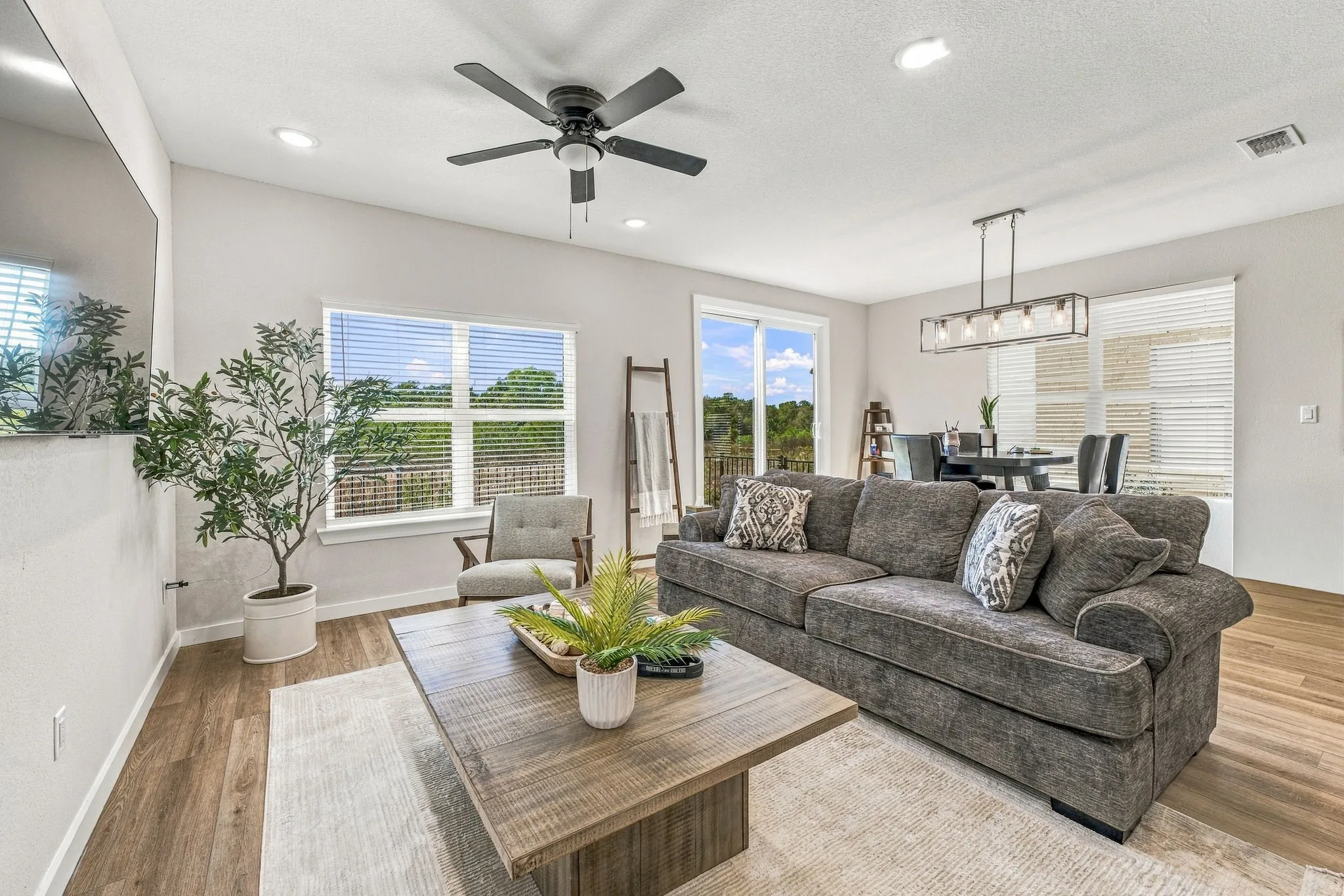Open-concept interior featuring wood-finish flooring, recessed lighting, a matte black ceiling fan, and a linear pendant light fixture