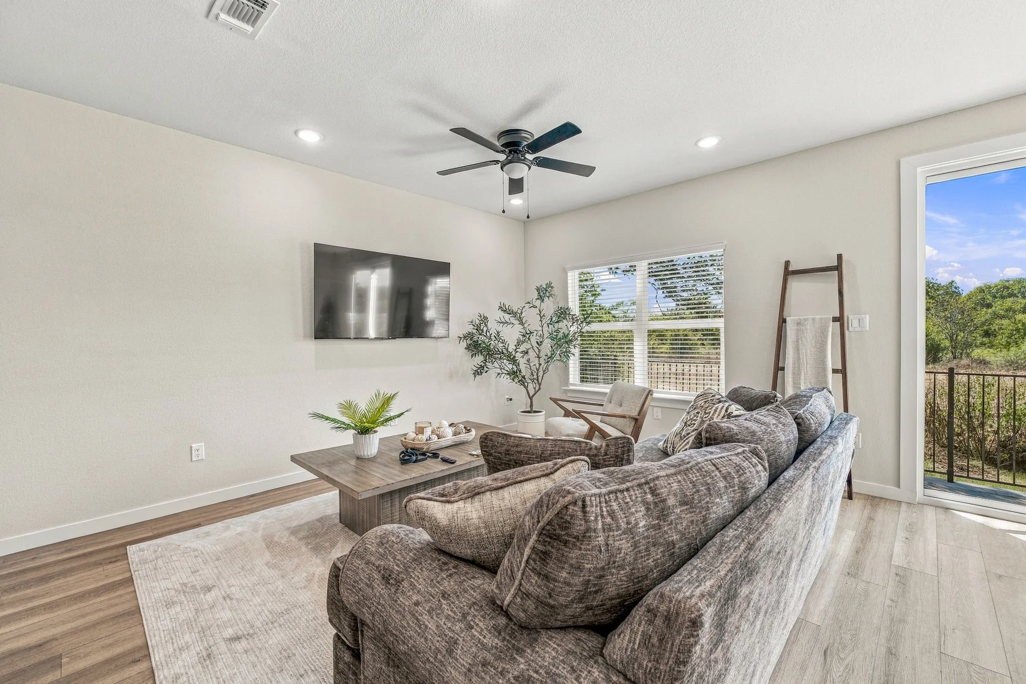 Living area featuring wood-finish flooring, a ceiling fan with integrated lighting, recessed lighting, and a multi-pane window