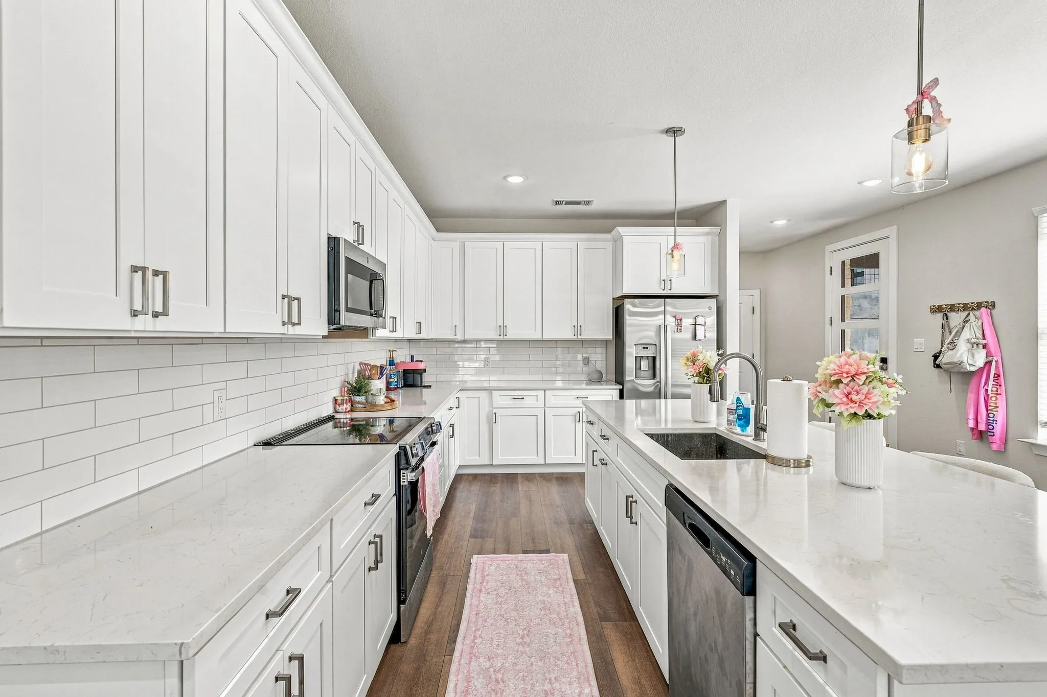Kitchen featuring white cabinetry, quartz countertops, a white subway tile backsplash, stainless steel appliances, and wood-finish flooring
