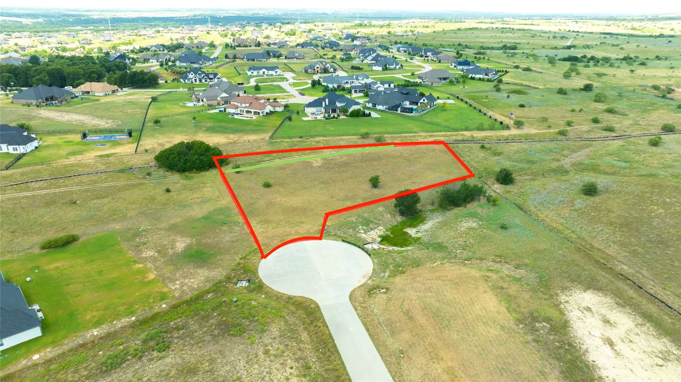 Vacant lot situated at the terminus of a paved cul-de-sac, featuring open topography and native vegetation