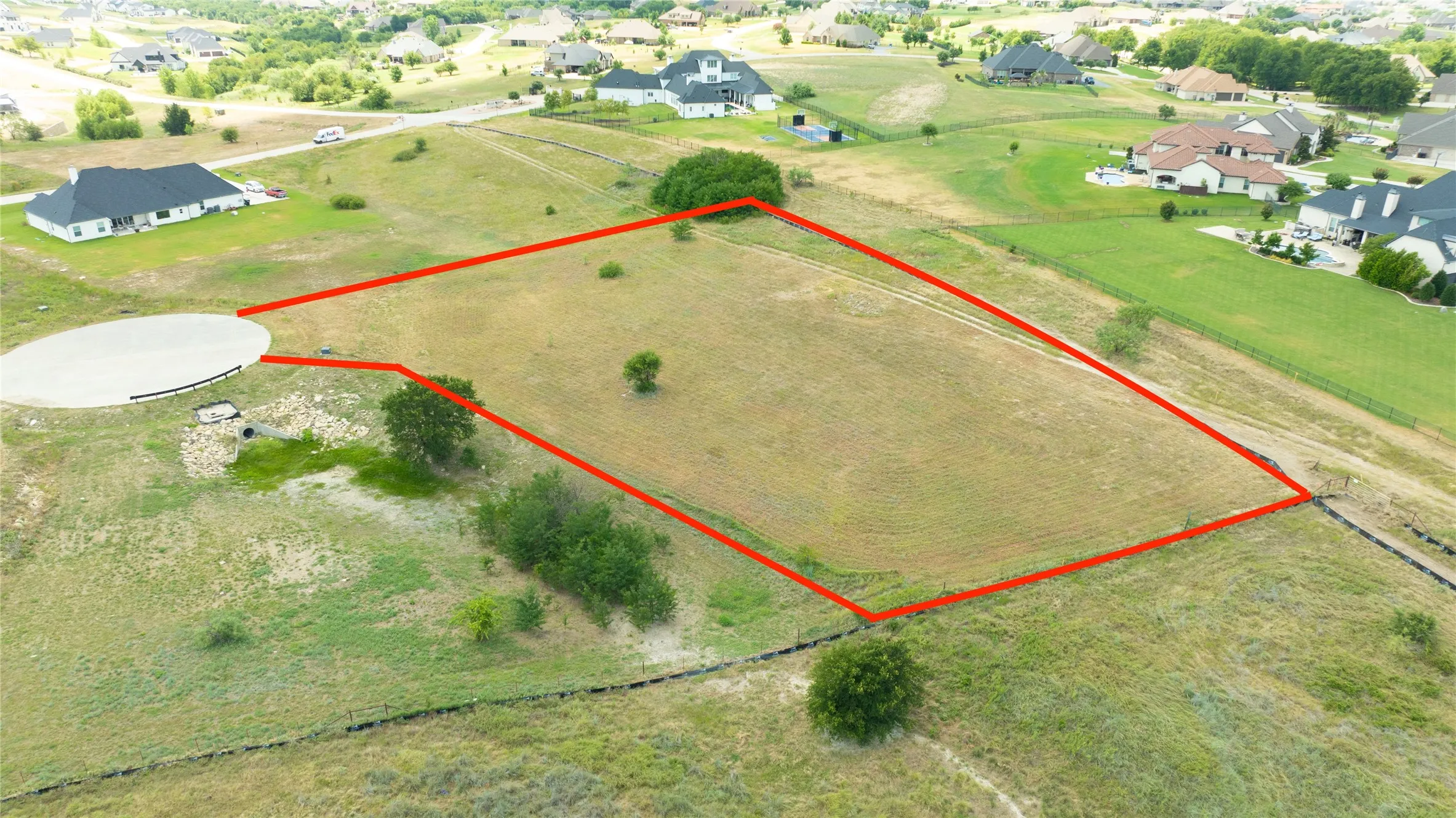 Expansive vacant land parcel featuring a circular concrete driveway approach and natural topography